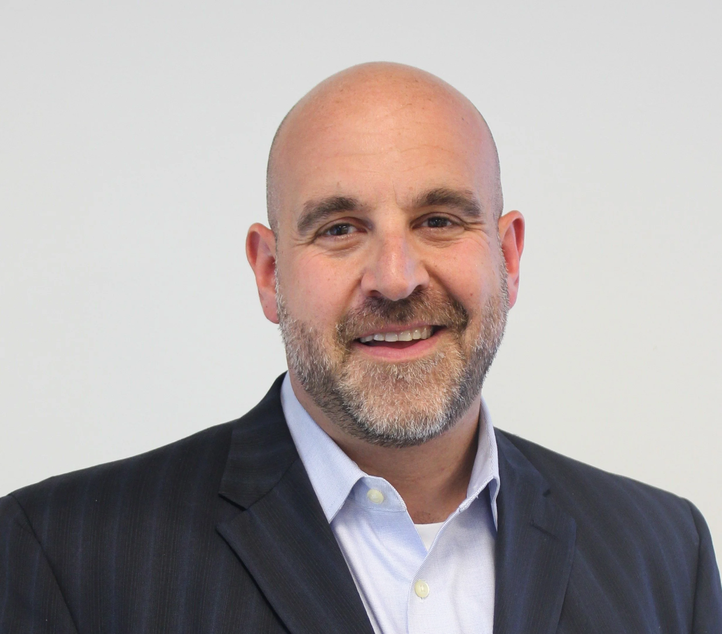 Bob smiling at the camera wearing a suit and dress shirt.