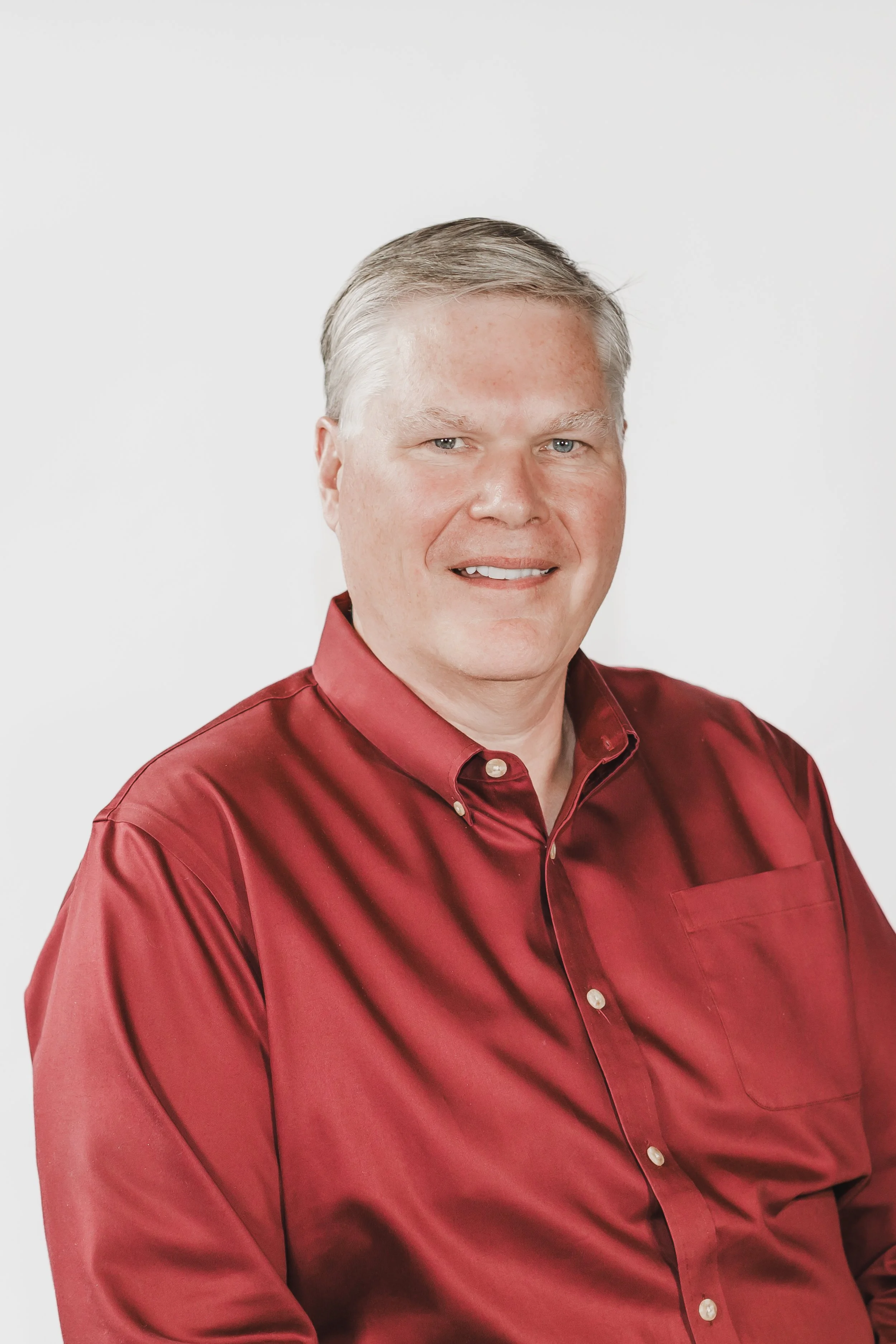 Winston smiling at the camera wearing a red button up shirt.