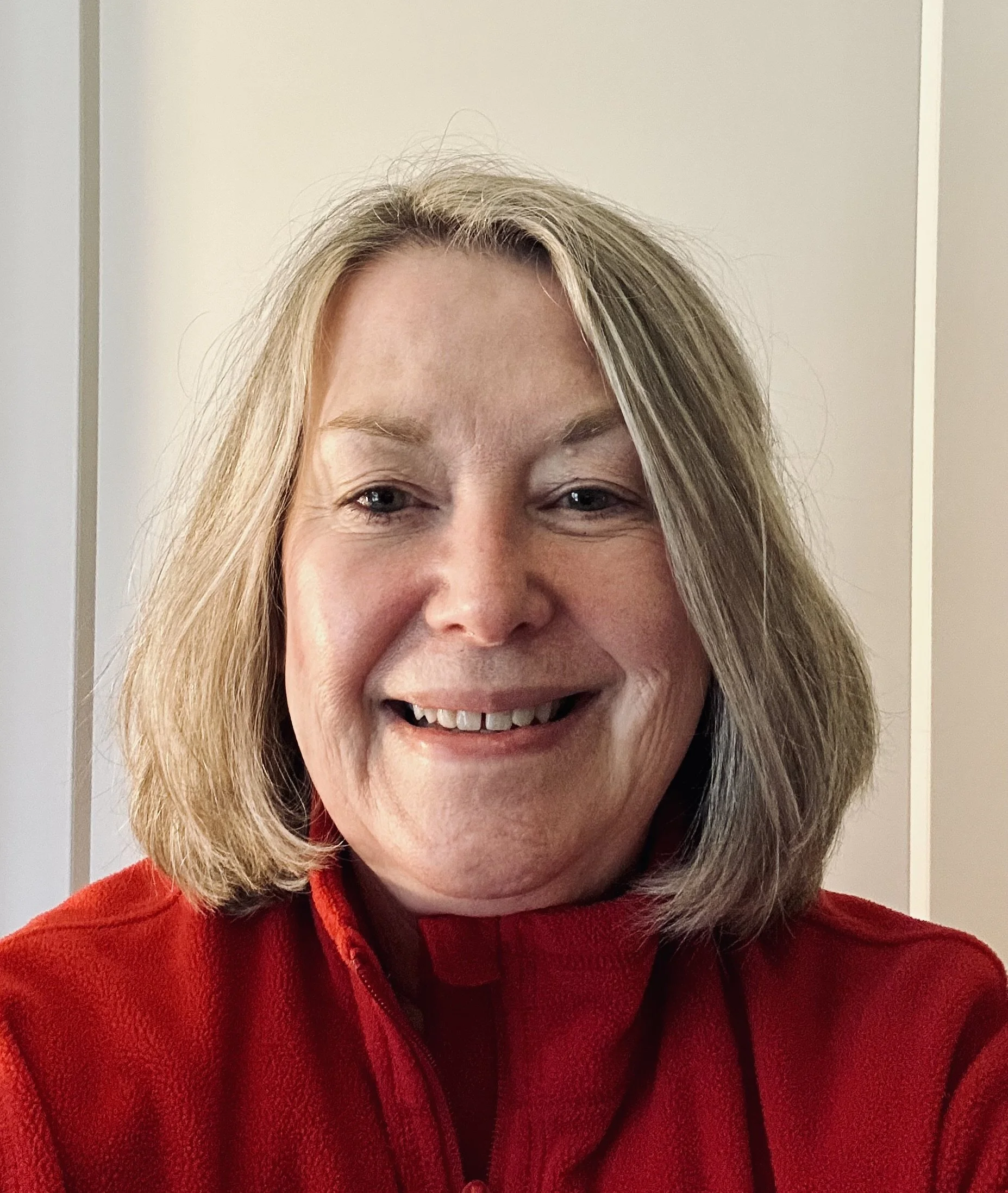 Barb smiling at the camera wearing a red top.
