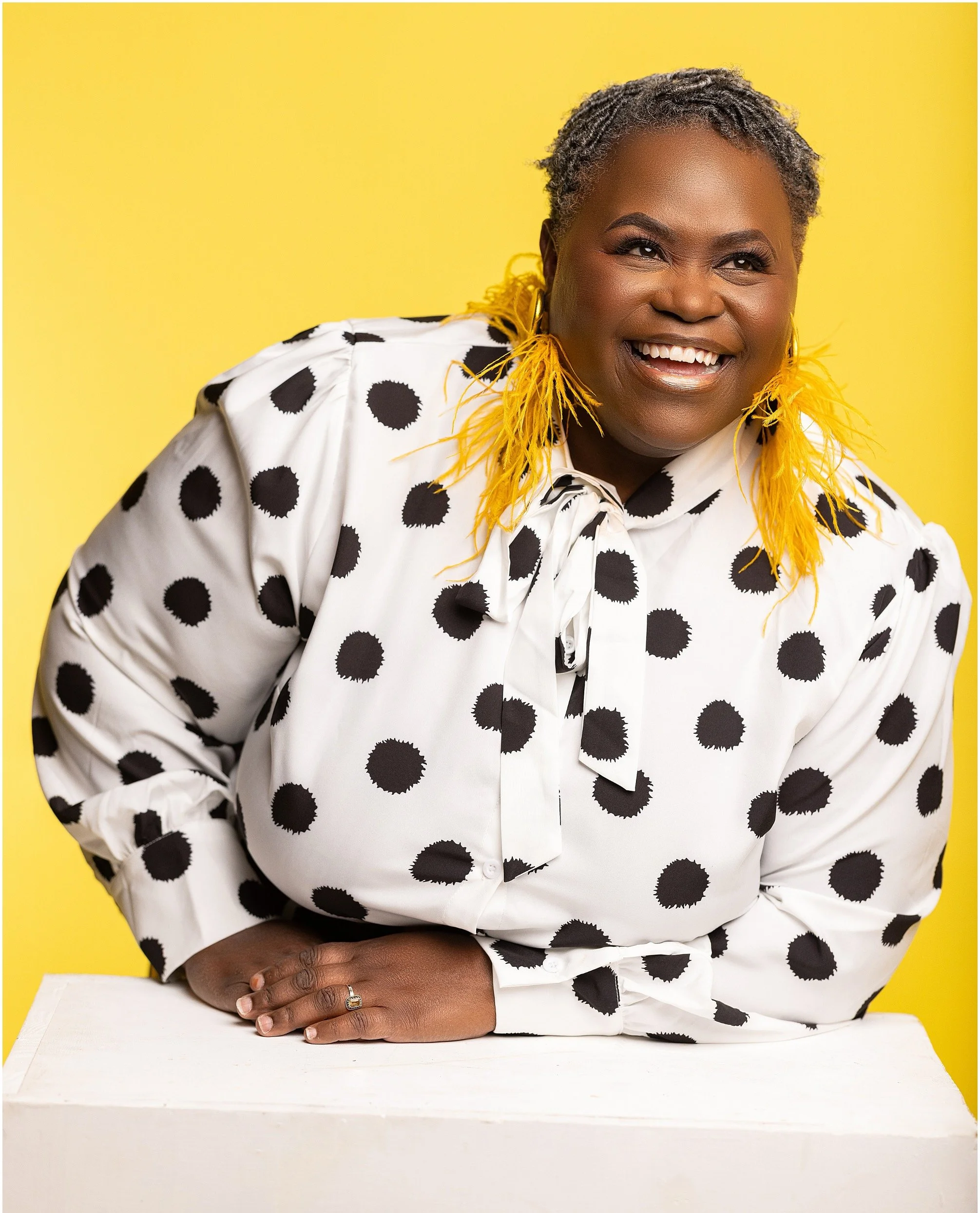 Jokeitha smiling off to the side wearing a black and white polka dot shirt.