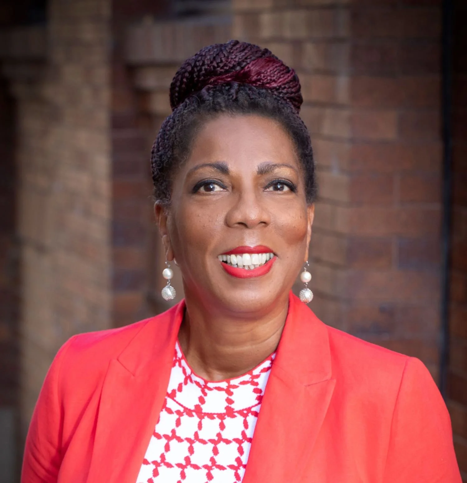Robin smiling at the camera wearing a red blazer.