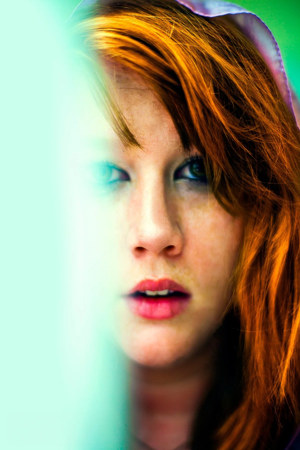 A close-up portrait of a woman with red hair, partially obscured by a translucent light green overlay on the left side of the image.