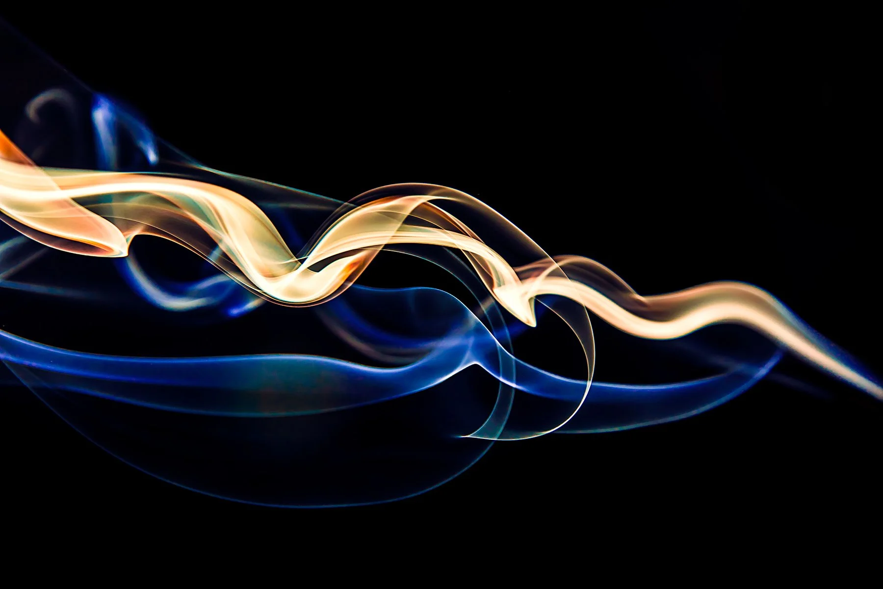 Colorful streaks of light in shades of blue, orange, yellow, and cream swirling against a black background.