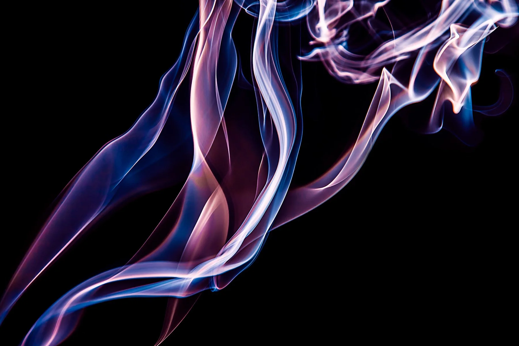 Colorful wisps of smoke or light in shades of pink, purple, and blue swirling against a black background.