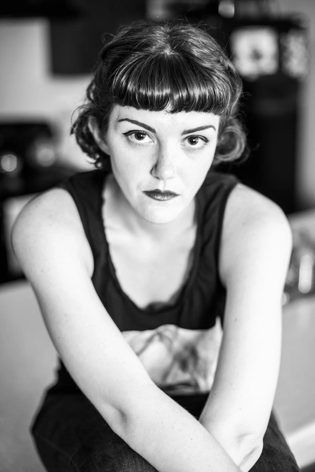 Black and white portrait of a woman with short, styled hair and dark lipstick, looking directly at the camera with a serious expression.