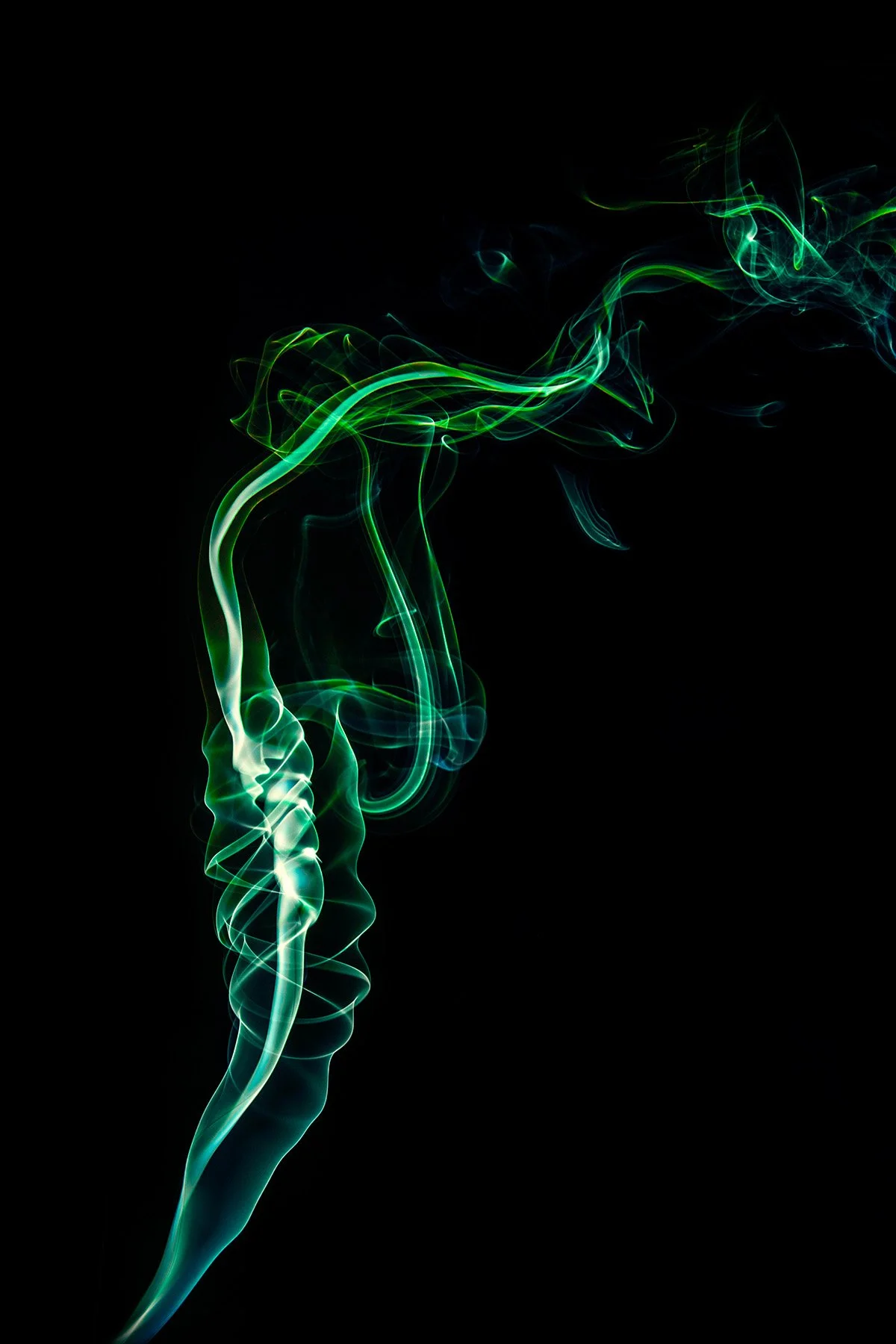Green and blue swirling wisps of smoke or vapor against a black background.