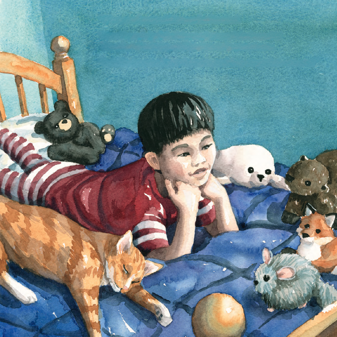 A young boy with short black hair laying on his stomach on a bed, surrounded by stuffed animals and a cat, with an orange ball nearby, looking thoughtfully.