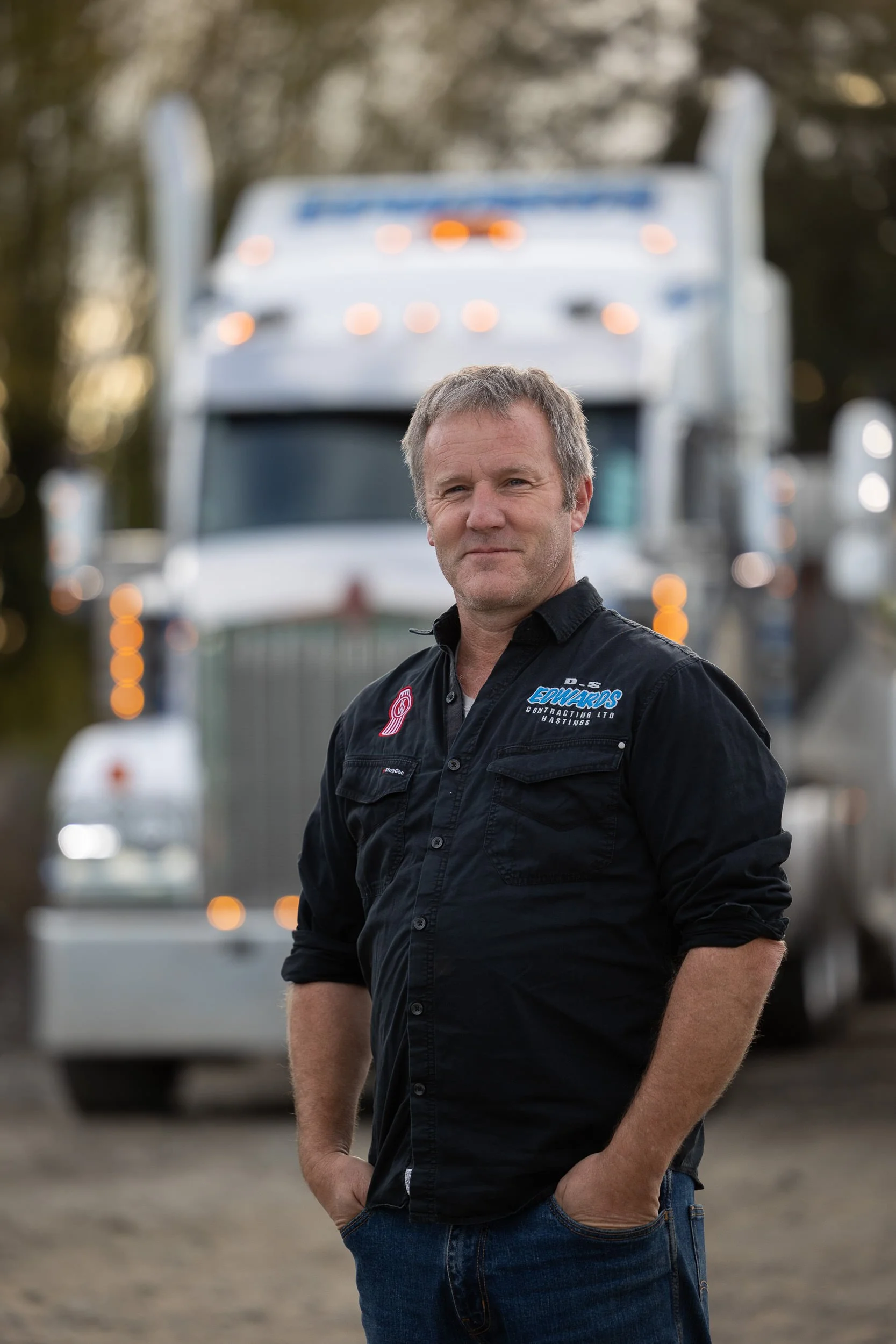 Damian Edwards from Edwards Contracting stands in front of his earthmoving trucks in the yard in Hastings, Hawkes Bay.