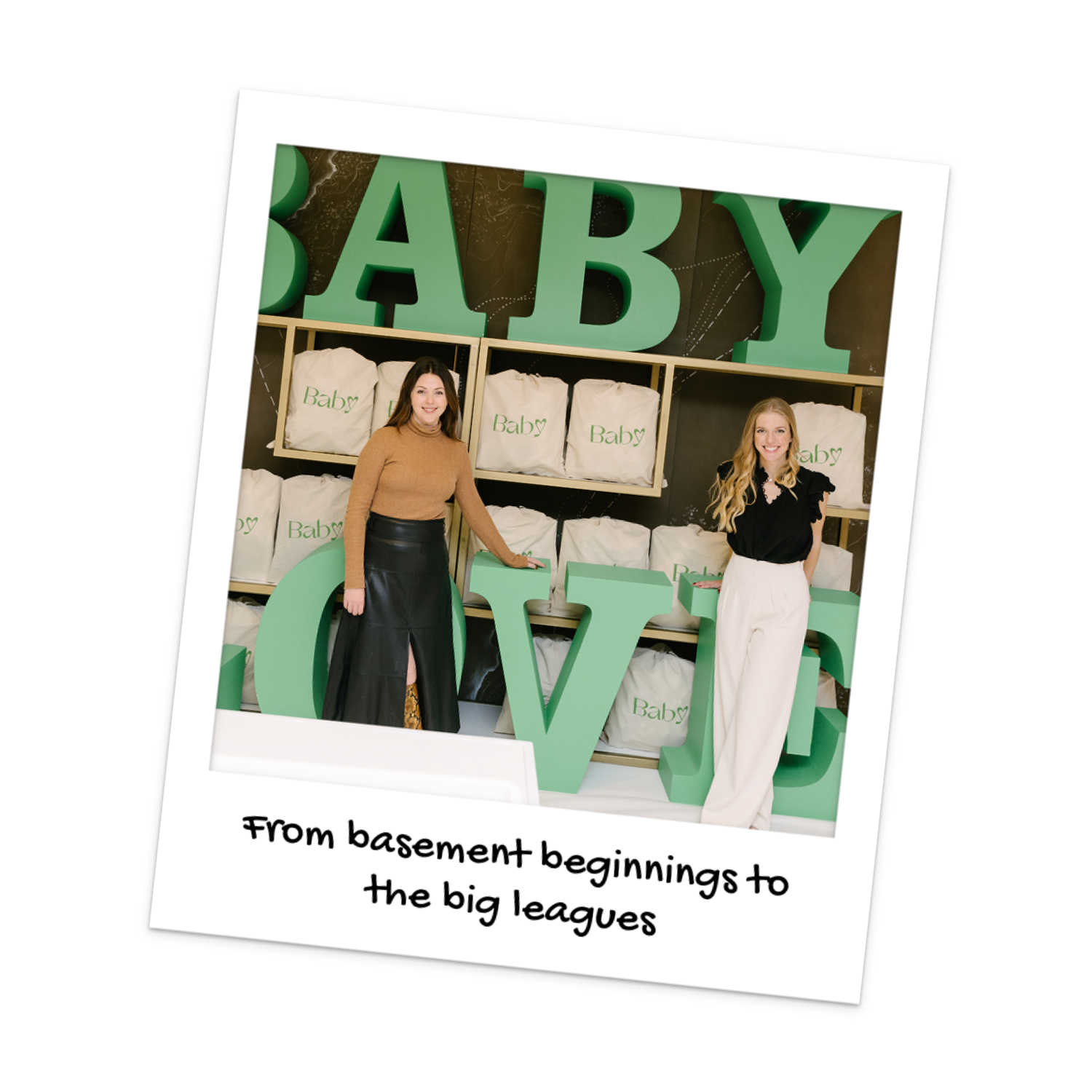 Baby Love's co-founders, Julia and Tanya, stand in front of a Baby Love sign to celebrate becoming a registered charity