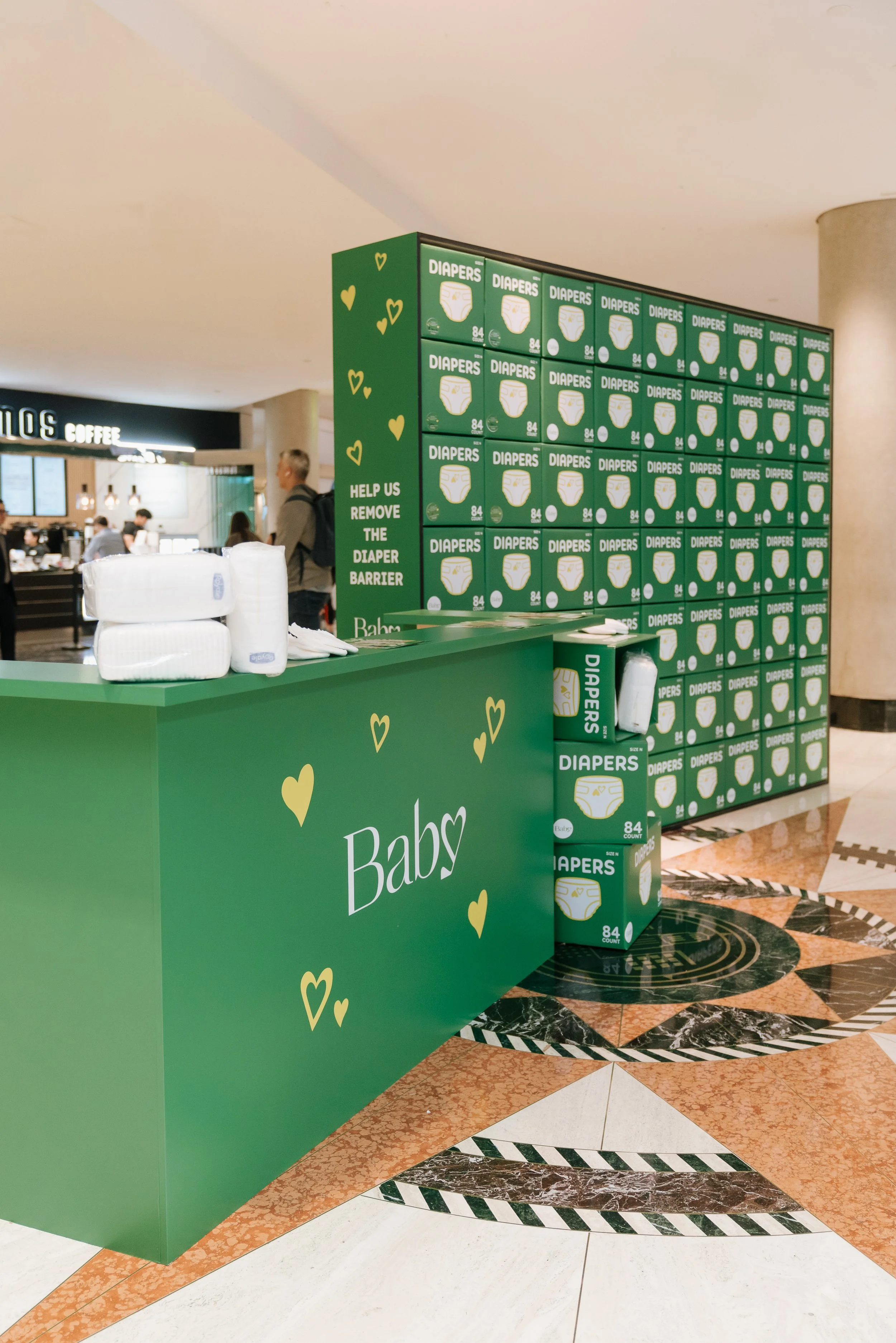 A large wall of diapers is built in a downtown location as a representation of the way lack of diaper access prevents parents from going to work
