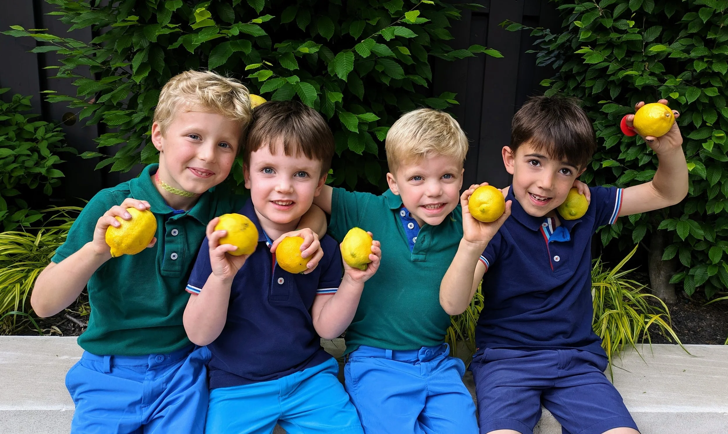 4 boys, The Lemon Lads, are shown at their lemonade stand, a fundraiser for Baby Love