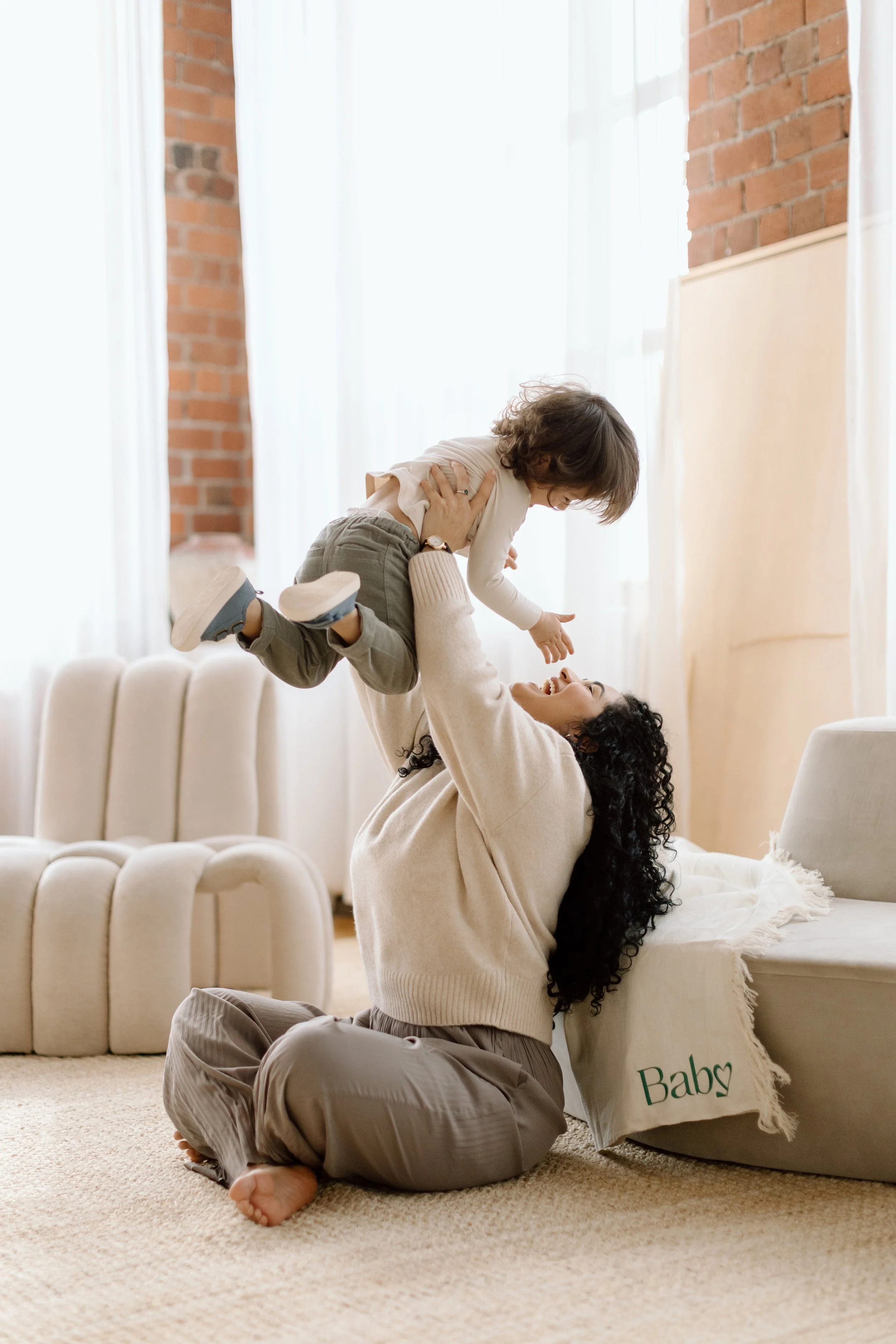A Baby Love mom, Yosselyne, is shown joyfully lifting her son Nehemias