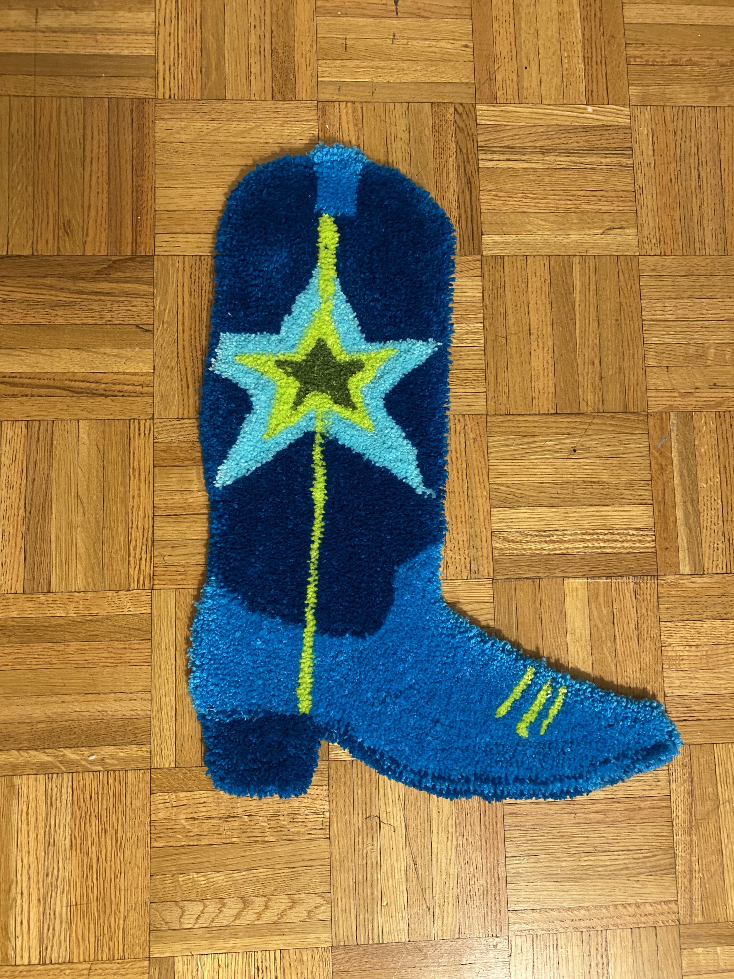 Colorful rug shaped like a cowboy boot with a star design, on a wooden floor.