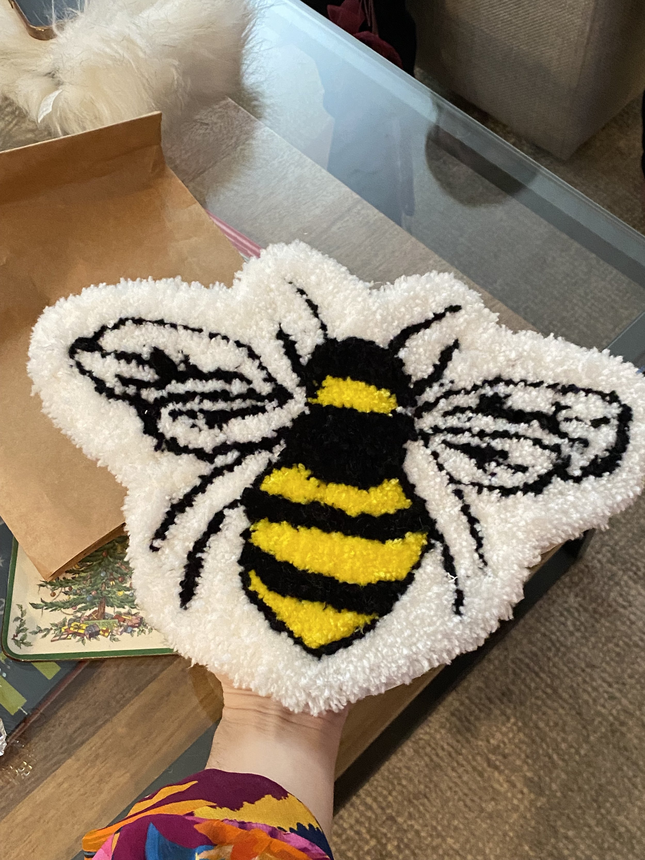 A small tufted rug of a bee on a white background.