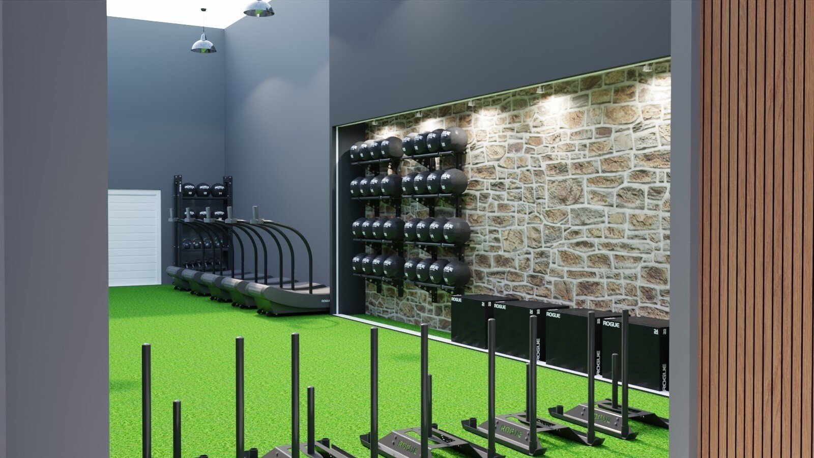 Inside a modern gym with artificial green turf, featuring a rack of black medicine balls on a brick wall, multiple black plyometric boxes, and several black and gray rowing machines.