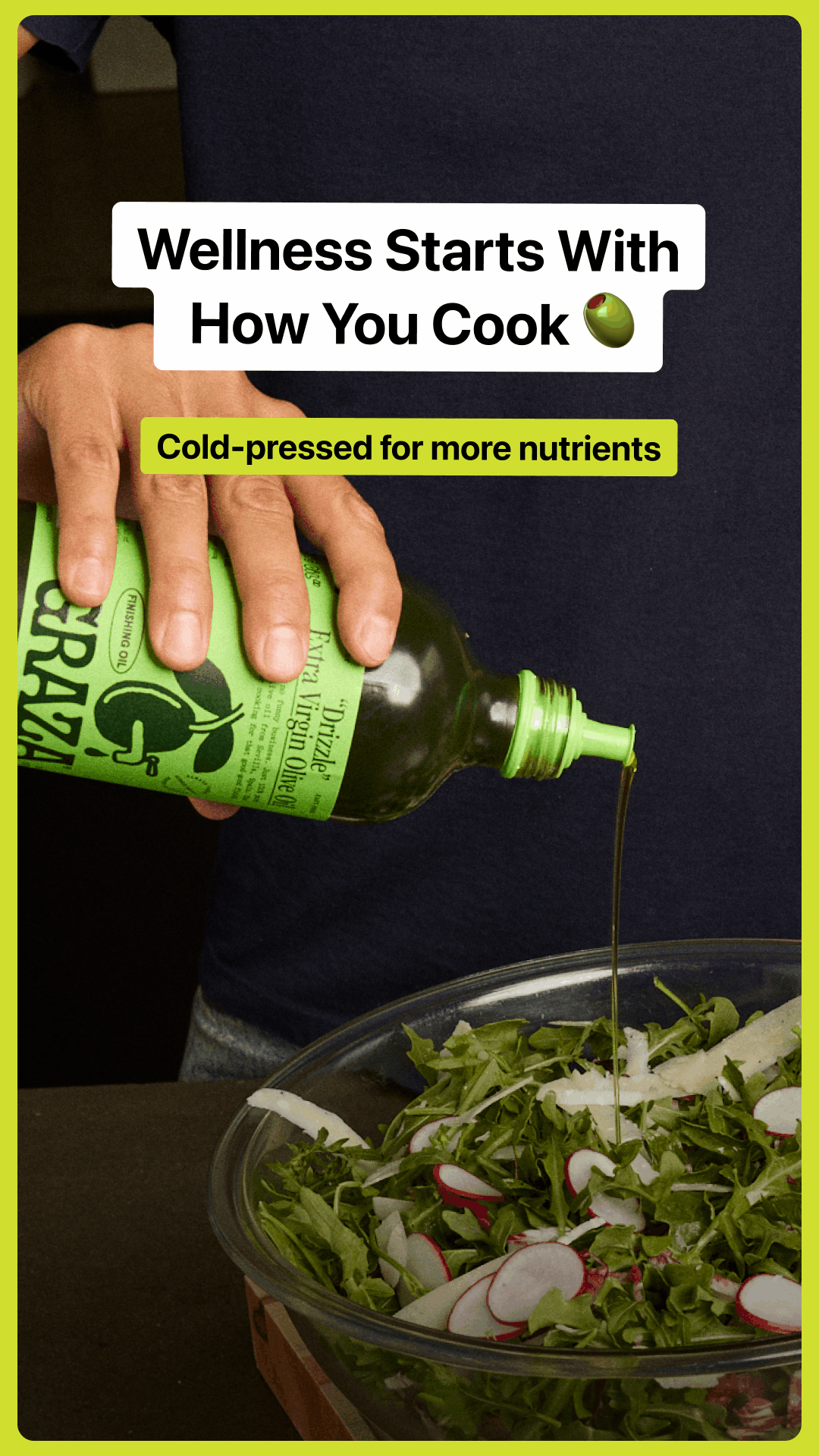 A person pouring extra virgin olive oil from a green bottle onto a fresh salad with arugula, radish slices, and cheese in a glass bowl.