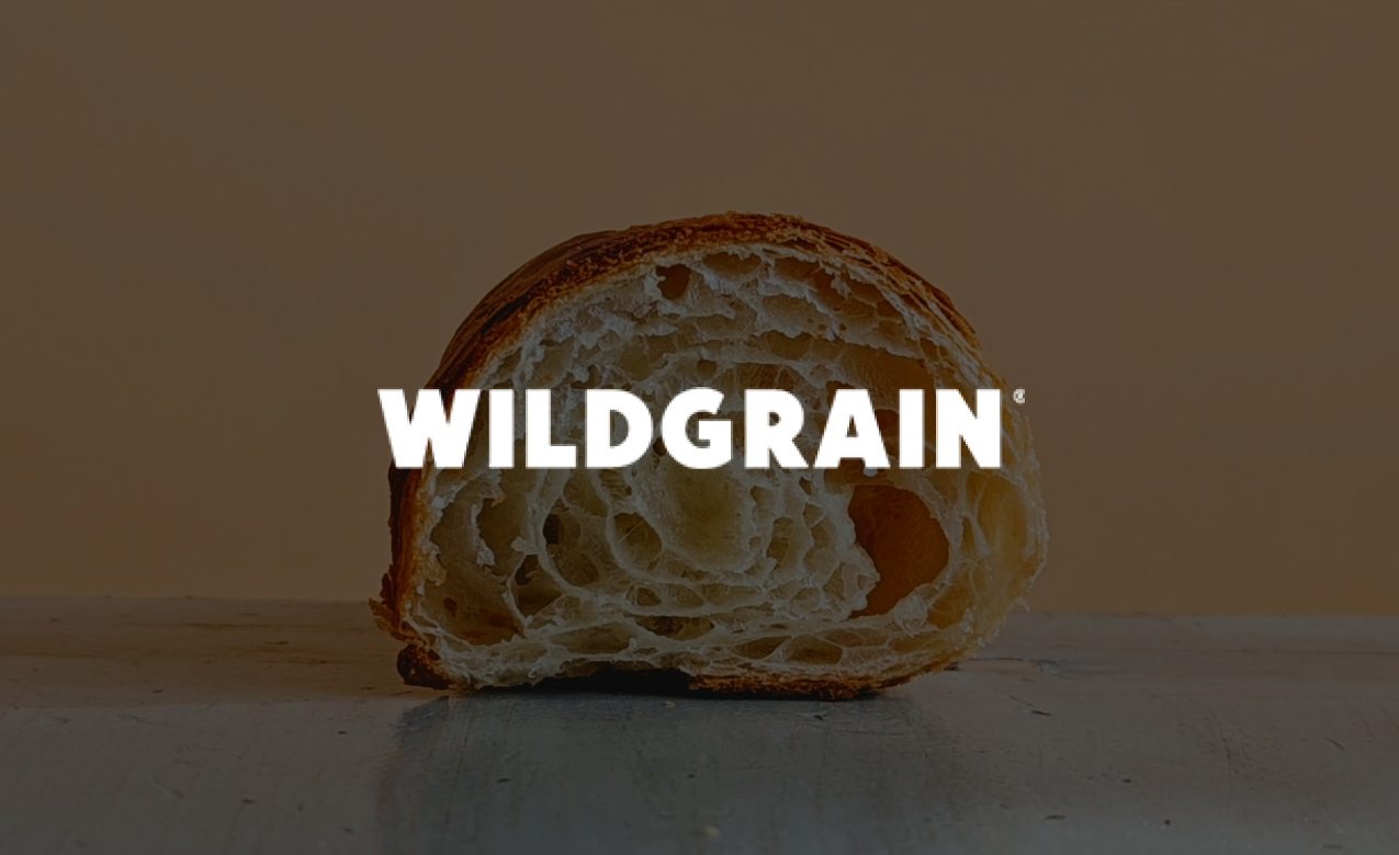 Close-up of a sliced piece of bread on a surface with the word 'Wildgrain' overlayed.