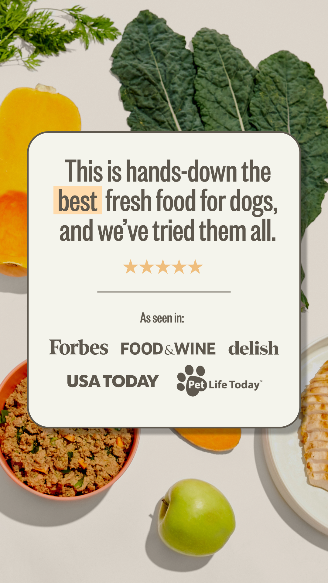 A display of fresh vegetables and food items including kale, carrots, an apple, and a plate of sliced cooked meat, with a text overlay promoting dog food.