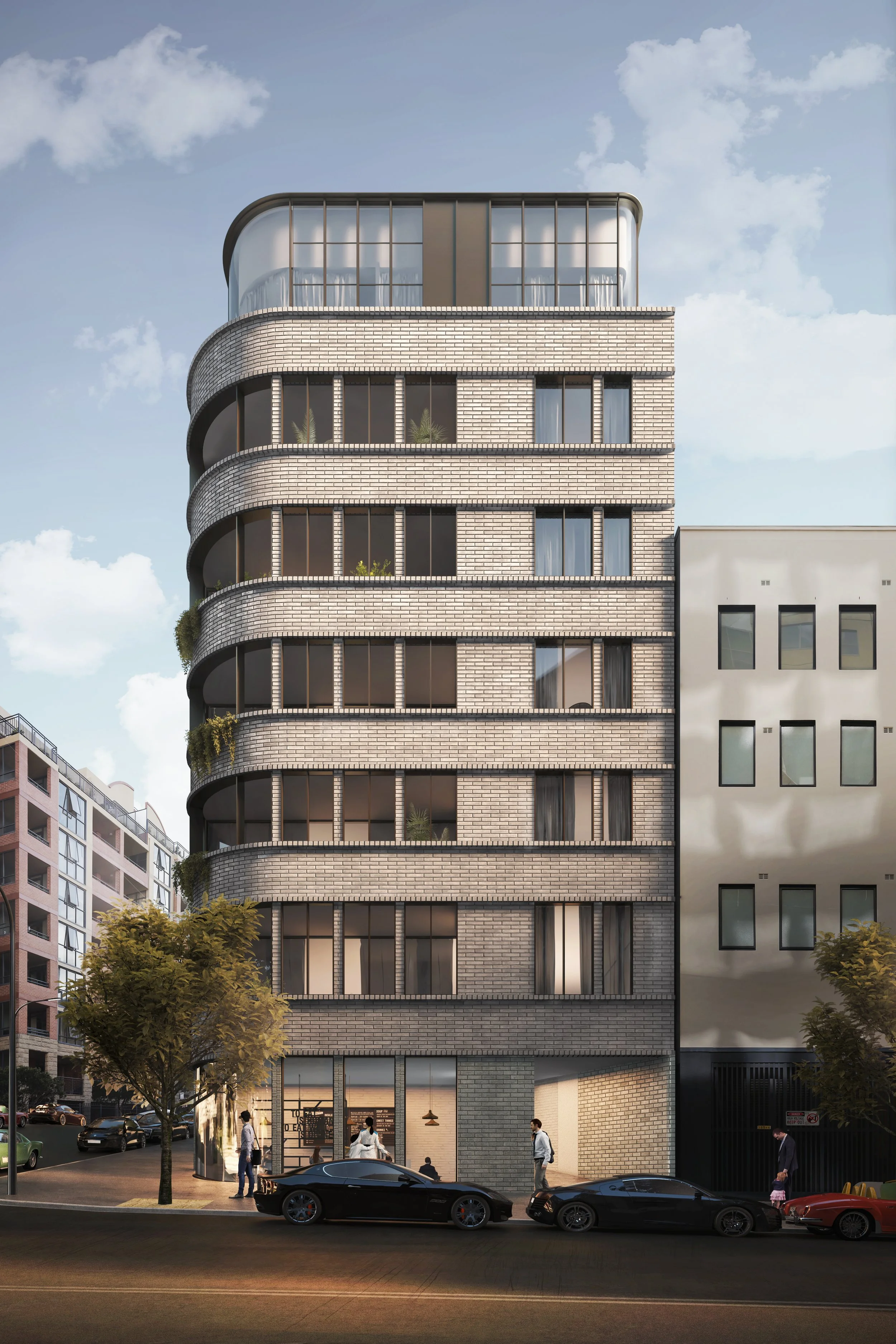 Modern mixed-use building with brick facade, corner rounded design, large glass windows, and a ground floor with retail space, in an urban setting with parked cars and pedestrians.