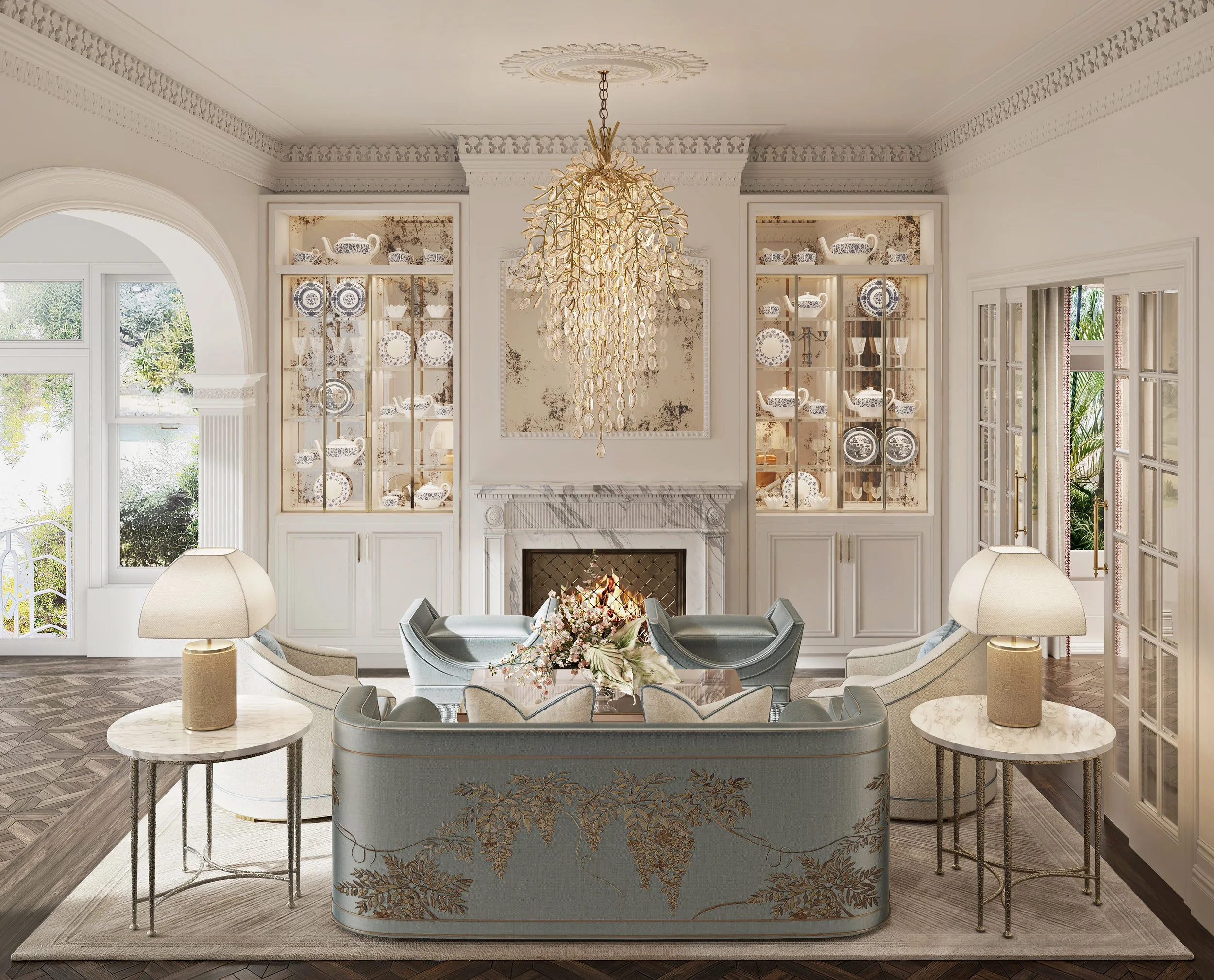 Elegant living room with a marble fireplace, glass display cabinets with china, a chandelier, and a sofa set arranged around a coffee table with flowers.