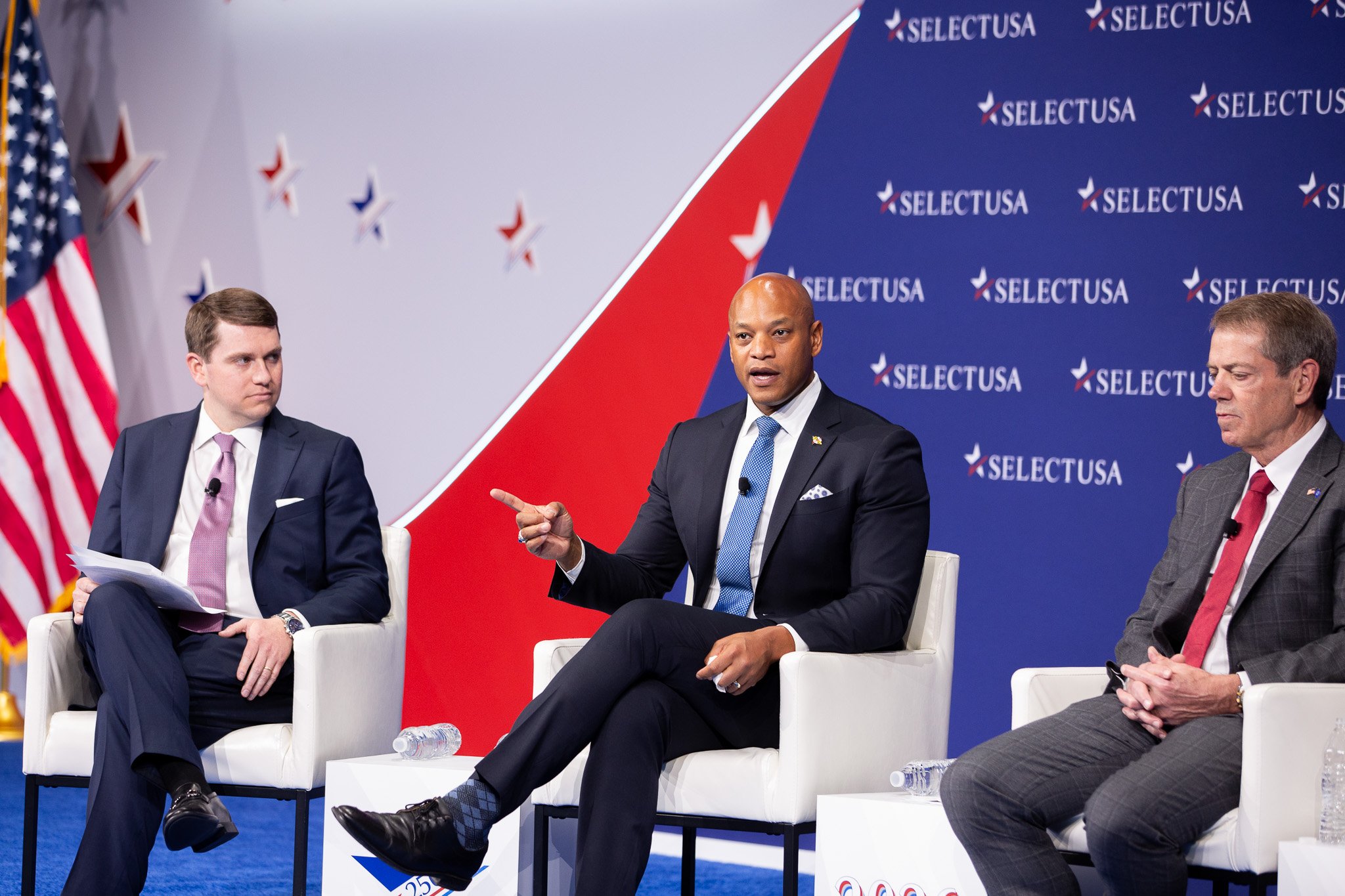 A panel discussion unfolds during the SelectUSA Investment Summit, where three business leaders engage in a conversation on investment and economic development before a live audience. Captured with clean composition and crisp event coverage, the imag
