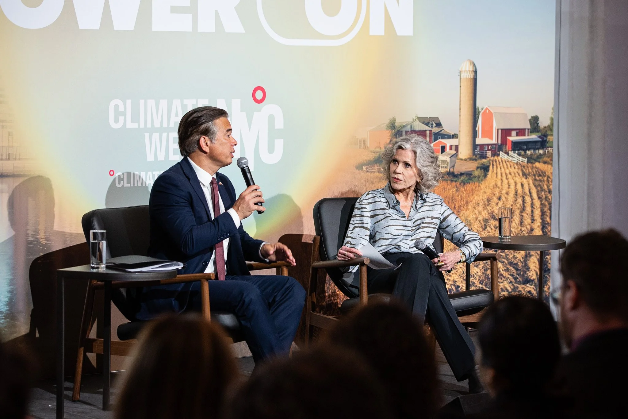 A featured speaker addresses the audience during a fireside chat at Climate Week NYC, engaging in a discussion on sustainability and the future of climate innovation. Seated on stage before a live audience, the speakers exchange ideas against a backd