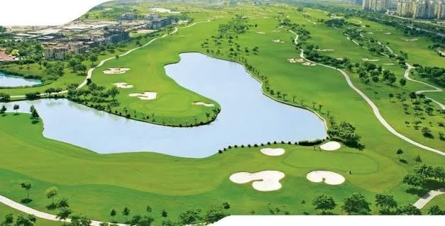Aerial view of a golf course with water hazards, sand bunkers, green fairways, and trees.