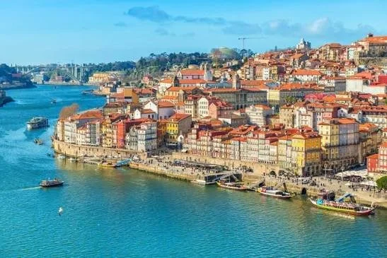 Colorful buildings along a waterfront with boats on a river, sunny sky