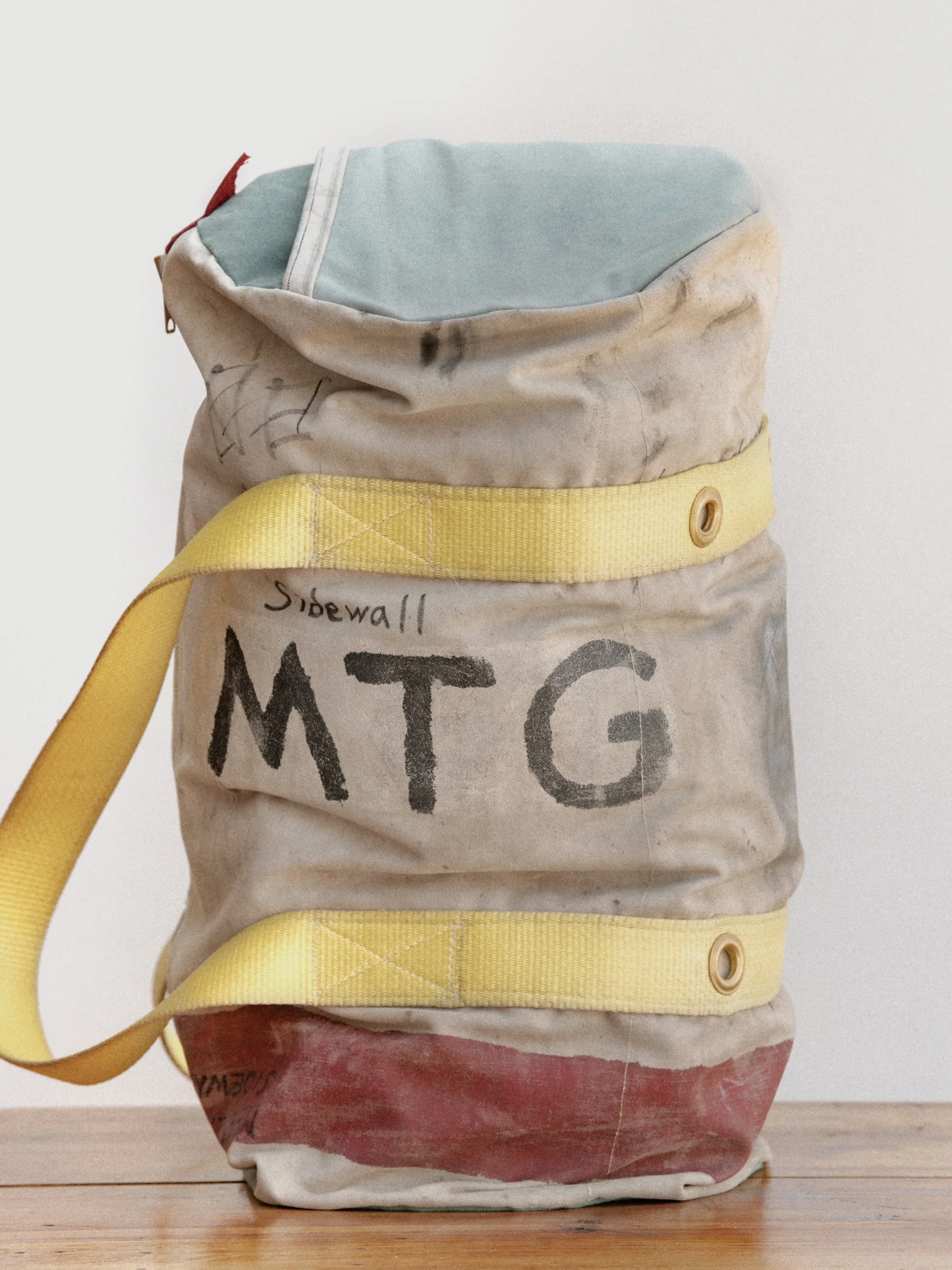 A used, painted fire hose with a yellow strap and graphics, resting on a wooden surface.