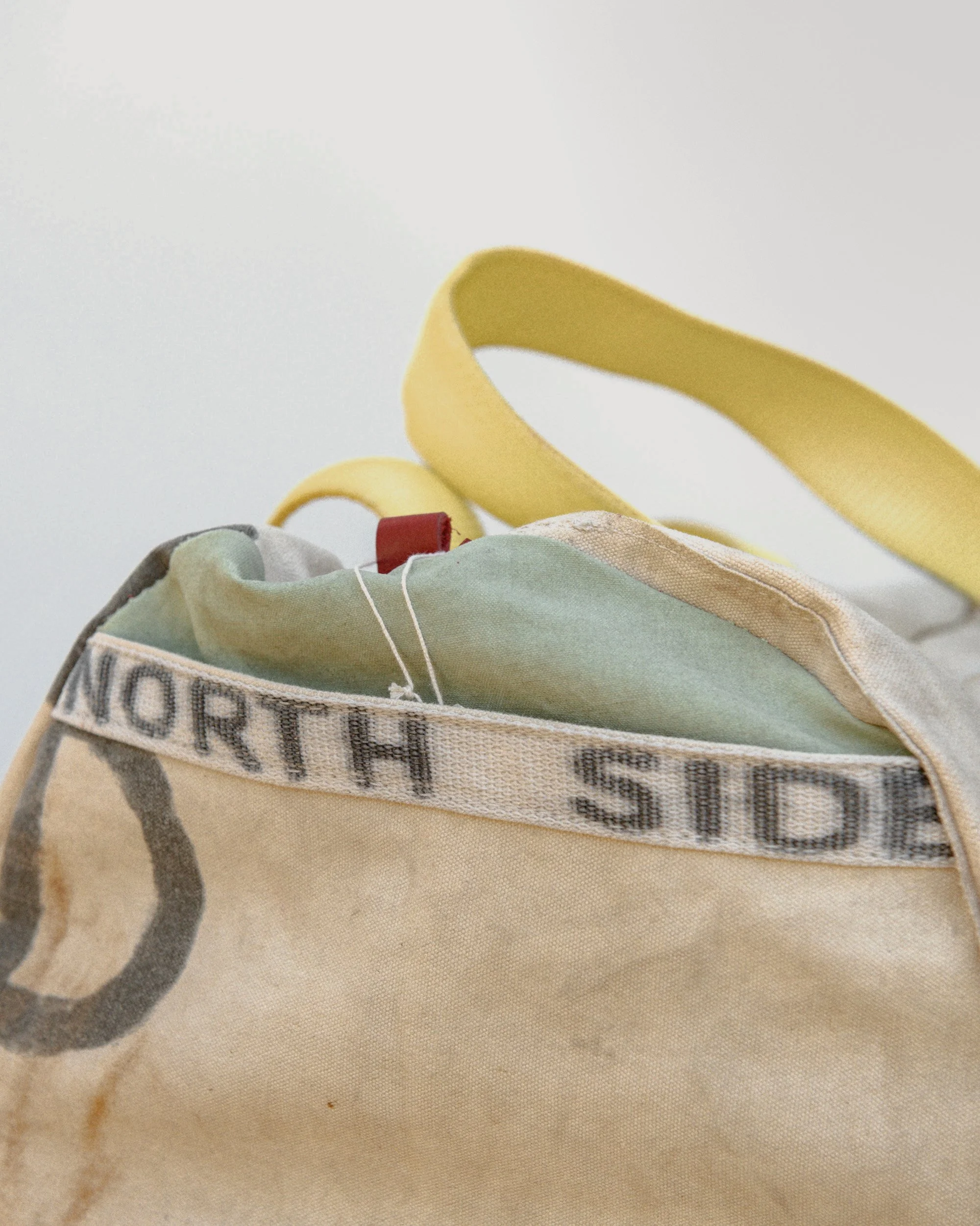 Close-up of a beige tote bag with yellow handles and a partially visible printed message.