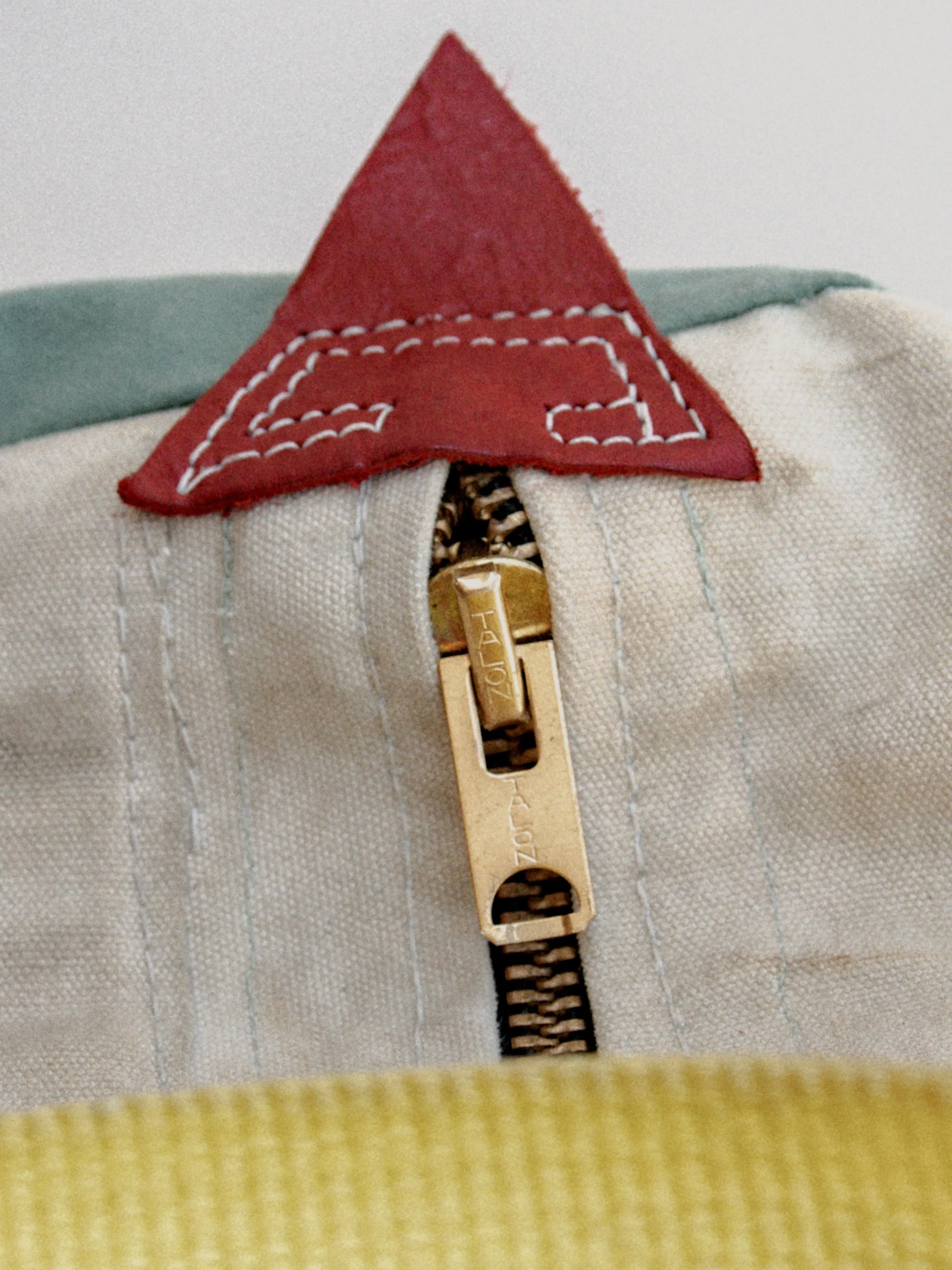 Close-up of a fabric zipper on a costume or clothing item with a red fabric triangle at the top.