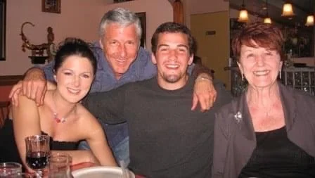 Four people smiling and posing for a photo at a dinner table in a restaurant.