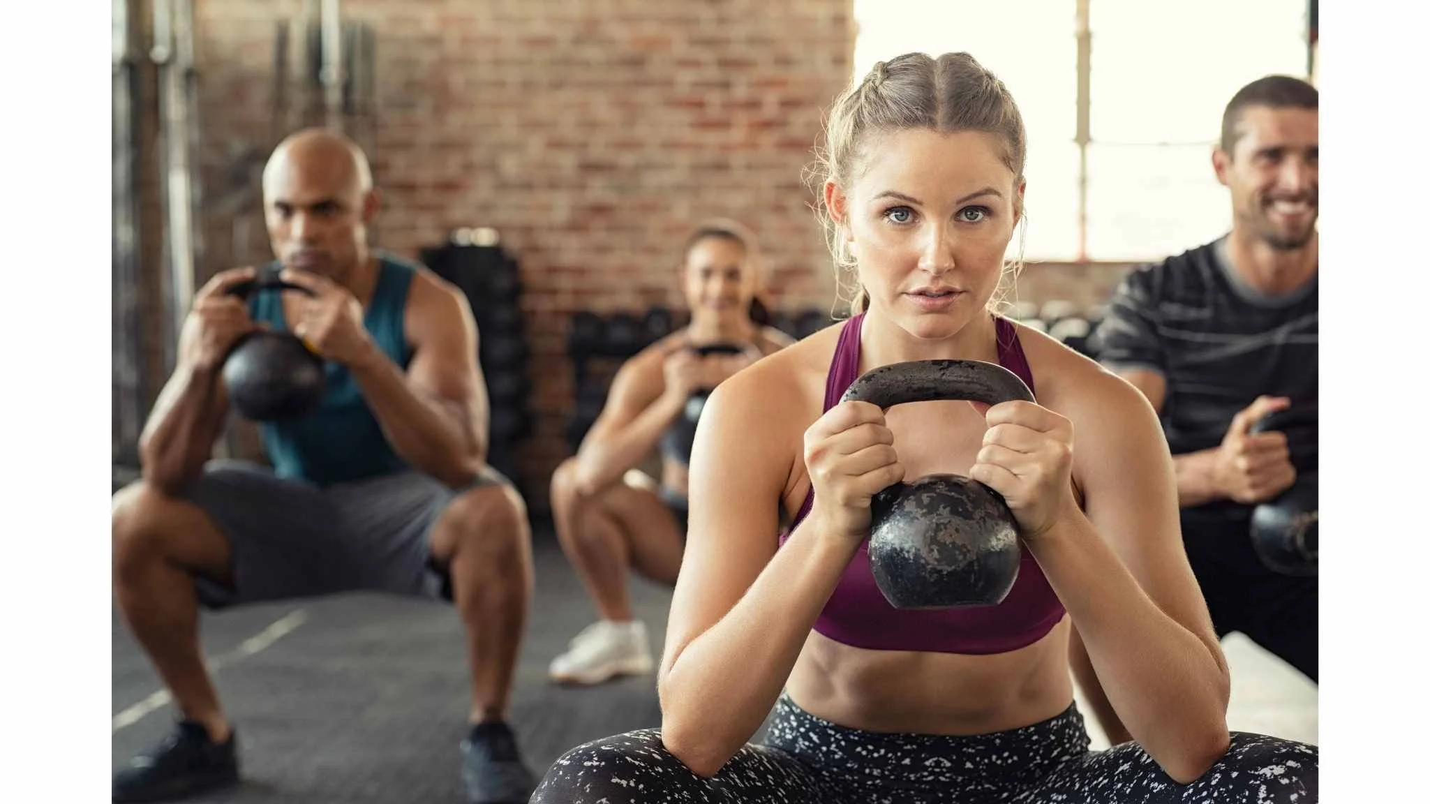 Group of people working out with kettlebells in a gym. Having had hyperbaric oxygen chamber therapy they have increased their stamina and endurance. 