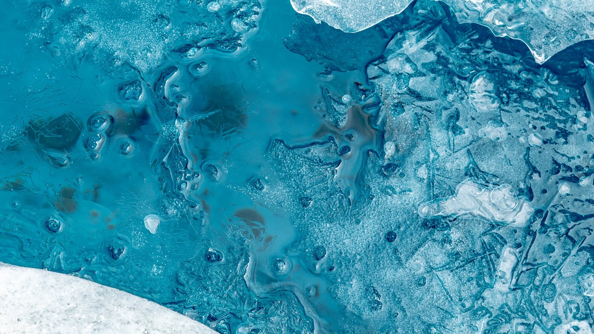 Close-up of cracked and frozen blue ice with bubbles and textured patterns.