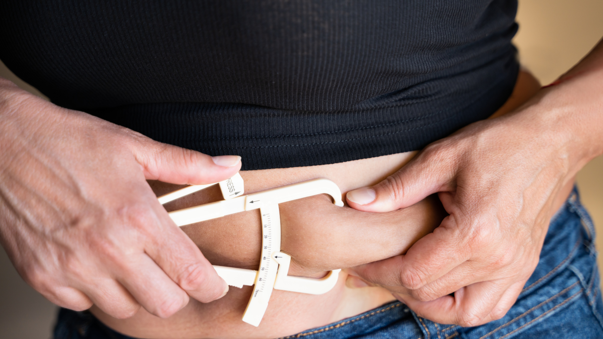 Skinfold calipers measuring subcutaneous fat on the lower abdomen