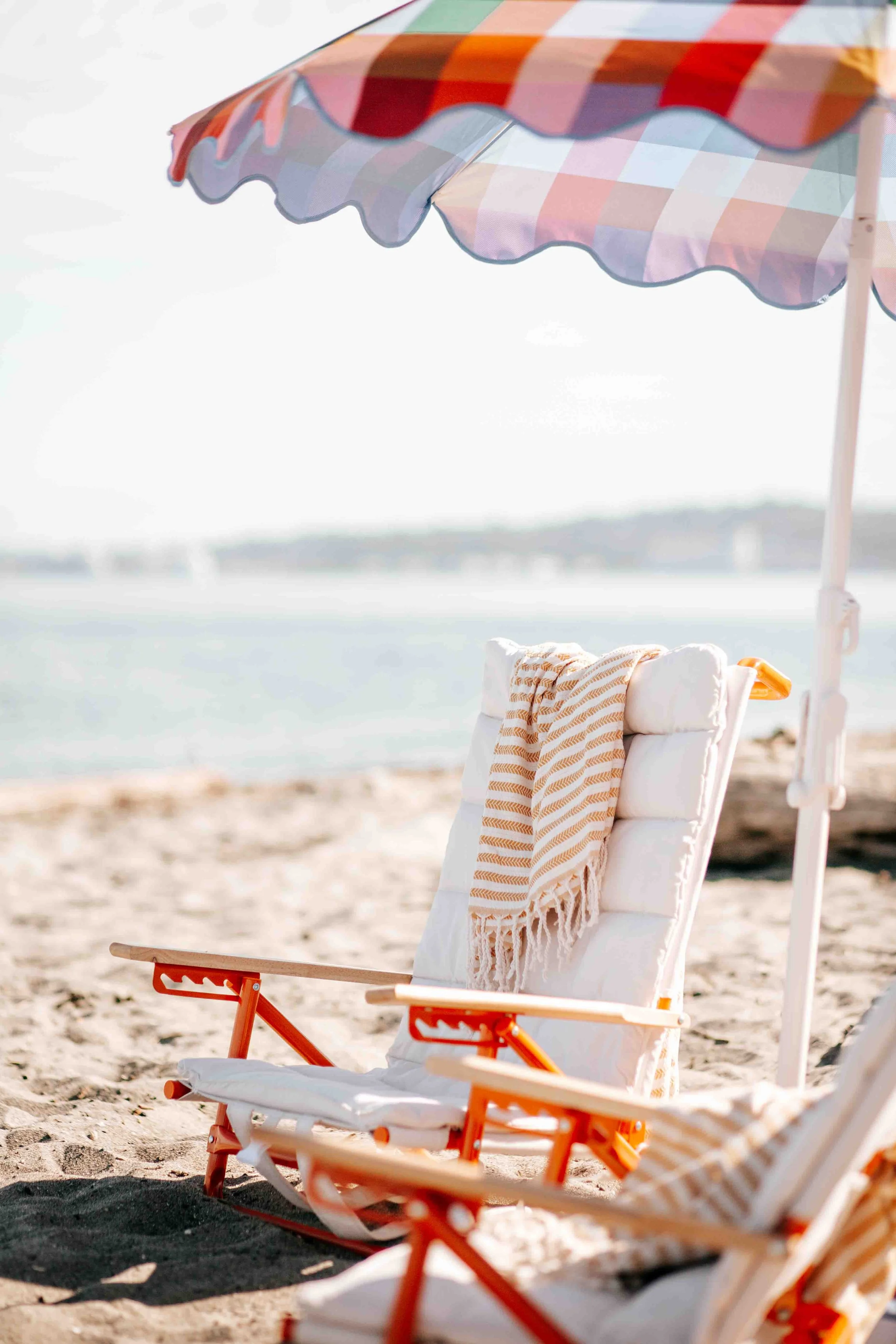 white and orange beach chairs with an umbrella on a sunny day at Alki Beach in Seattle