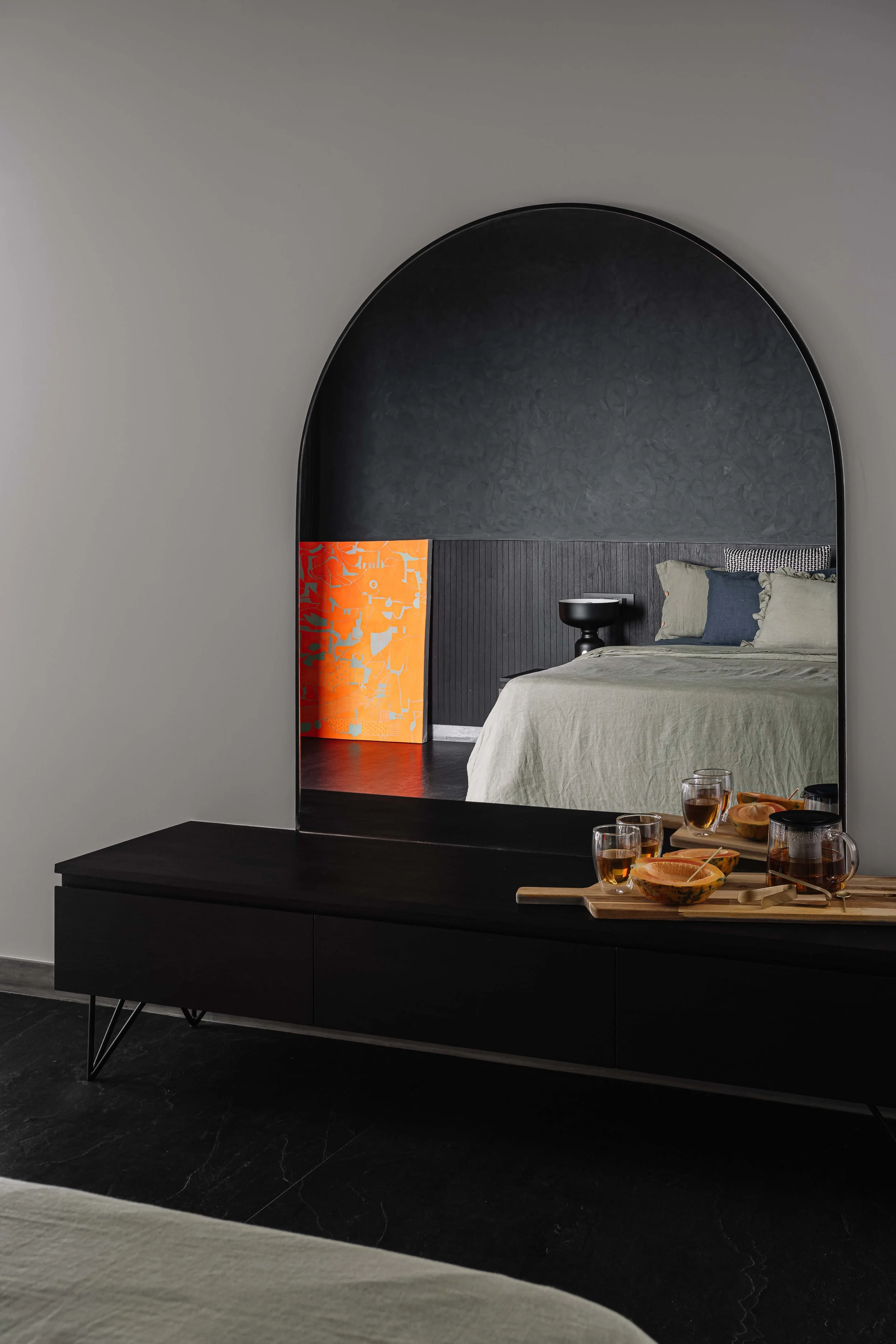 The guest bedroom is designed with a simple and practical layout, featuring open storage and large openings that frame views of the landscaped balcony and cityscape beyond, creating a calm and airy atmosphere.
