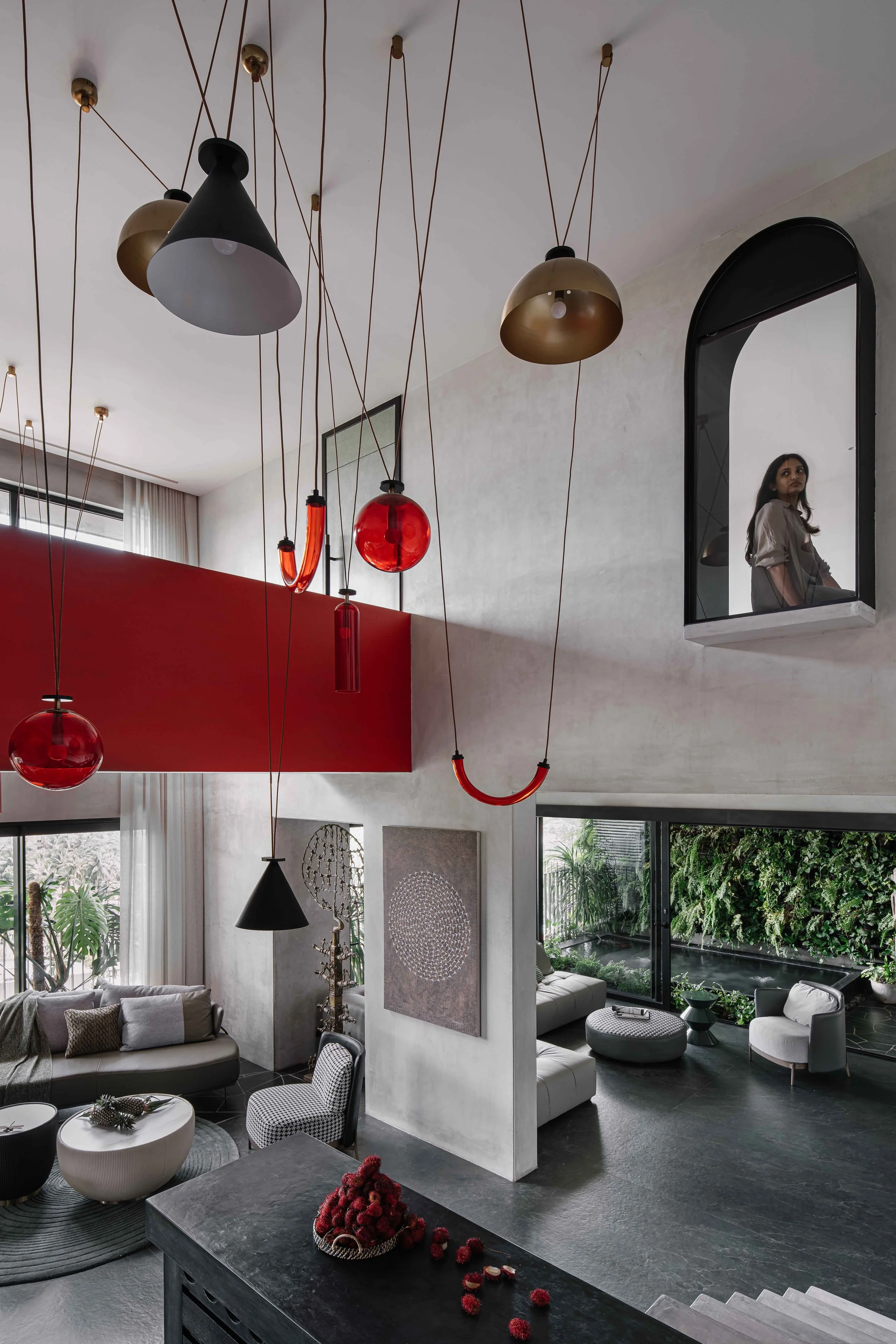 Minimalist staircase with sculptural lighting, monochrome finishes, and bold red accents at Gardens in the Sky, a Calicut residence designed by Workers of Art.