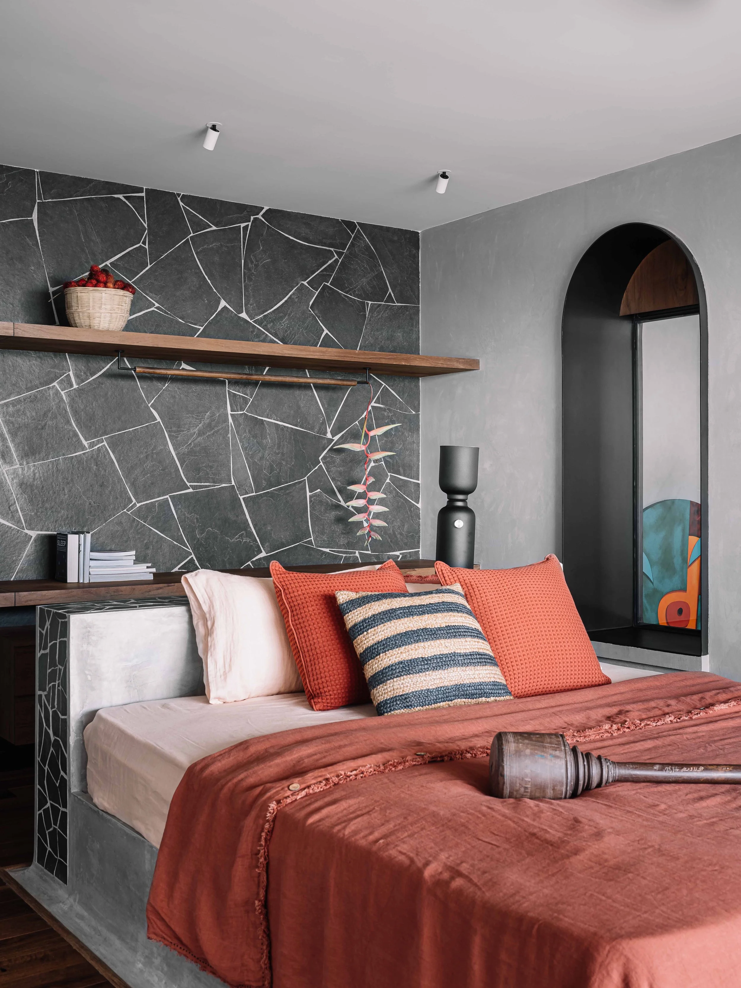 The master bedroom is designed as a calm and functional retreat, featuring a cast-in-place cement island bed, polished teak wood flooring, and a bay window that extends into the double-height space, maintaining visual connectivity while framing views