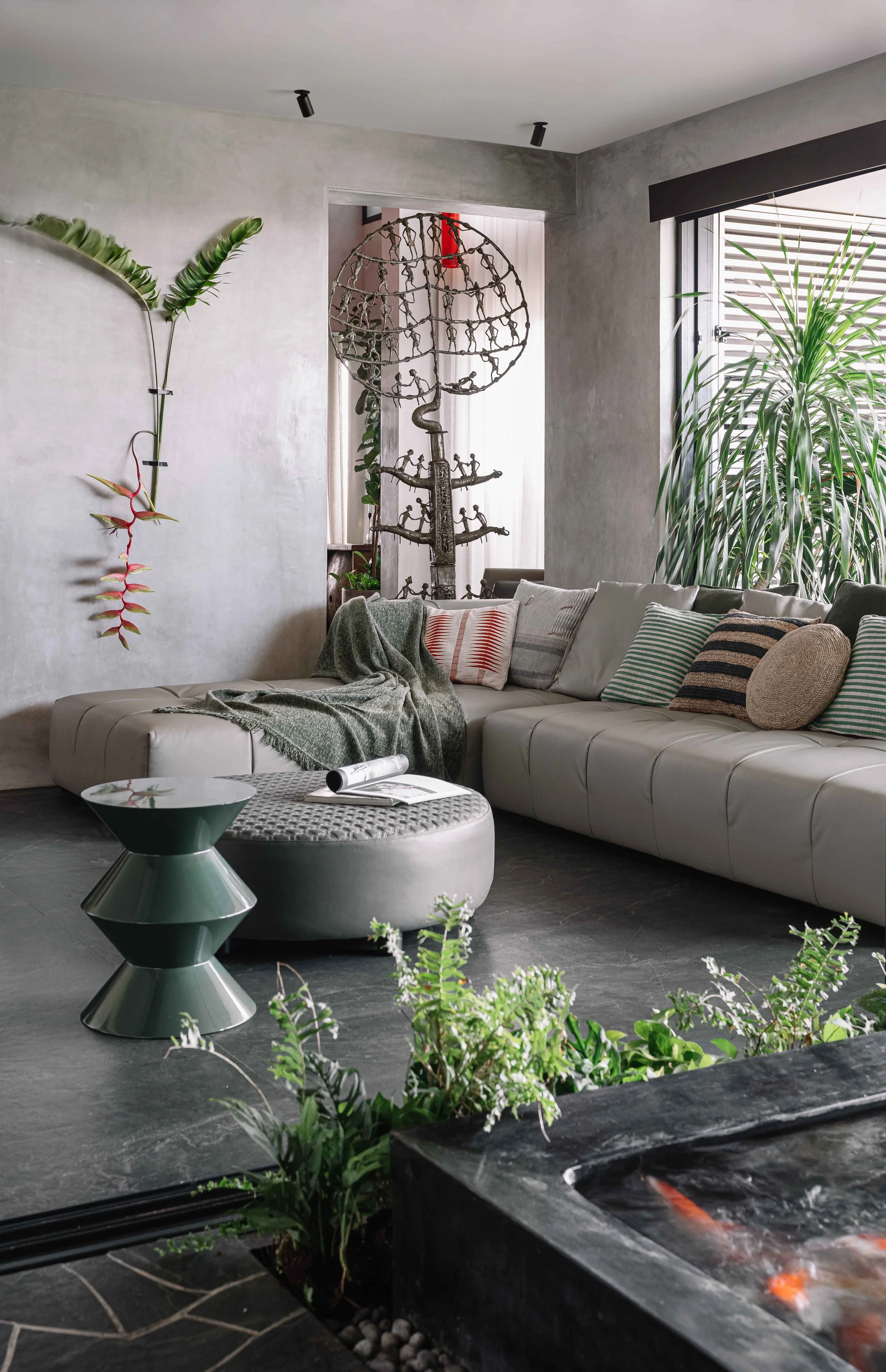 Contemporary living room with lush indoor planting, sculptural artwork, and layered textures at Gardens in the Sky, a Calicut residence designed by Workers of Art.