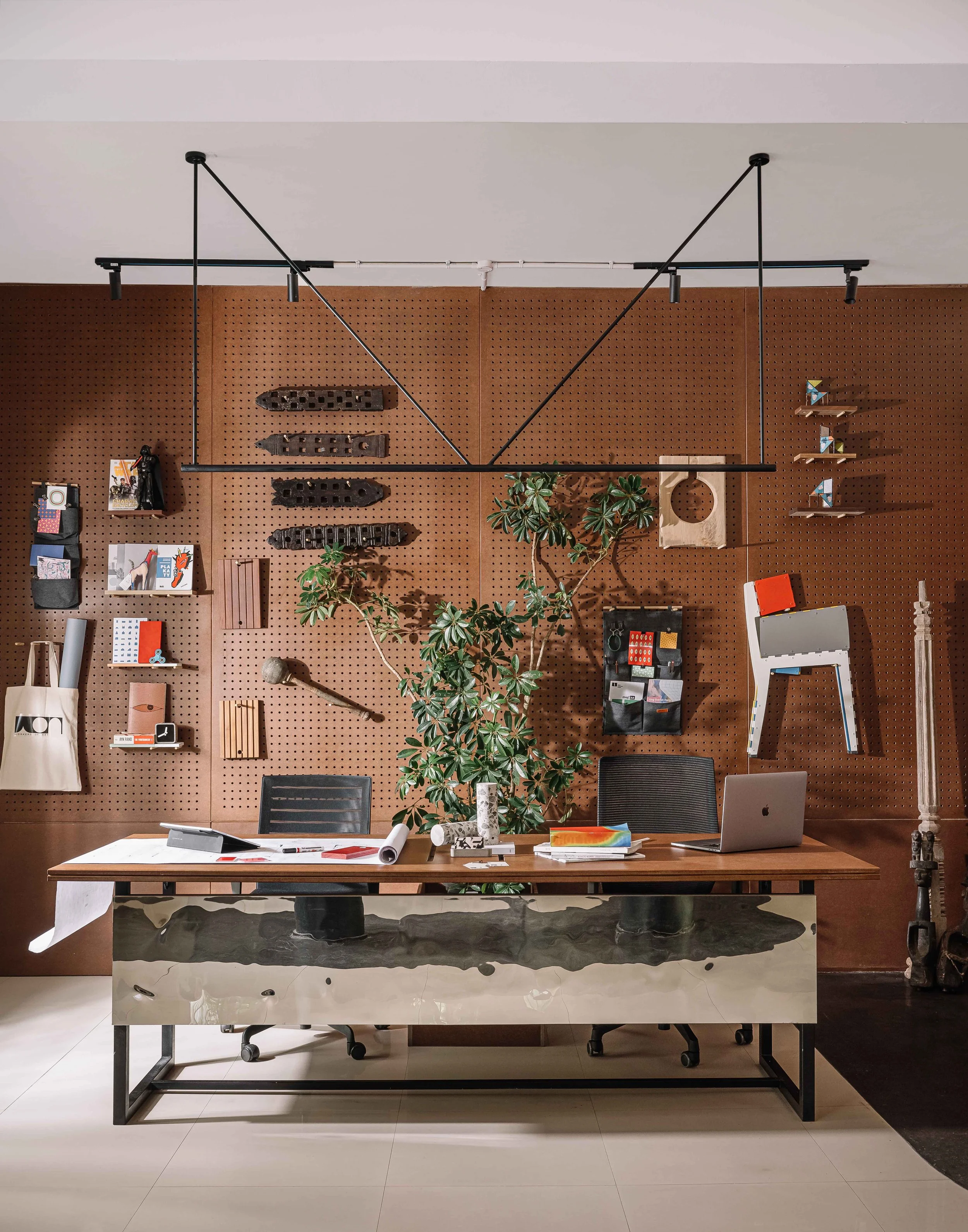 Studio workspace at Second Home by Workers of Art featuring a curated material wall, custom furniture, and contemporary office design in Kochi, India.