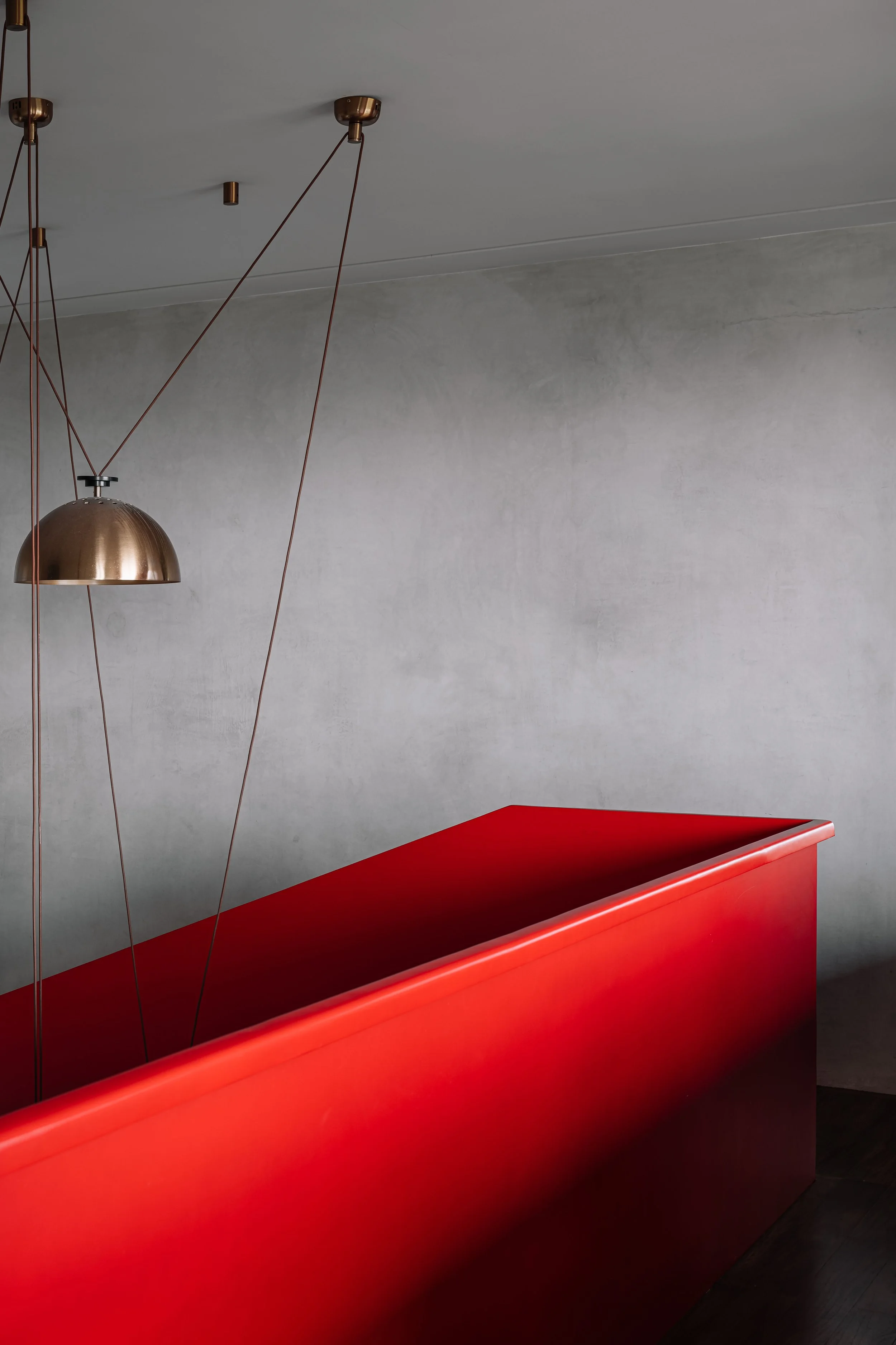 Minimalist staircase with sculptural lighting, monochrome finishes, and bold red accents at Gardens in the Sky, a Calicut residence designed by Workers of Art.
