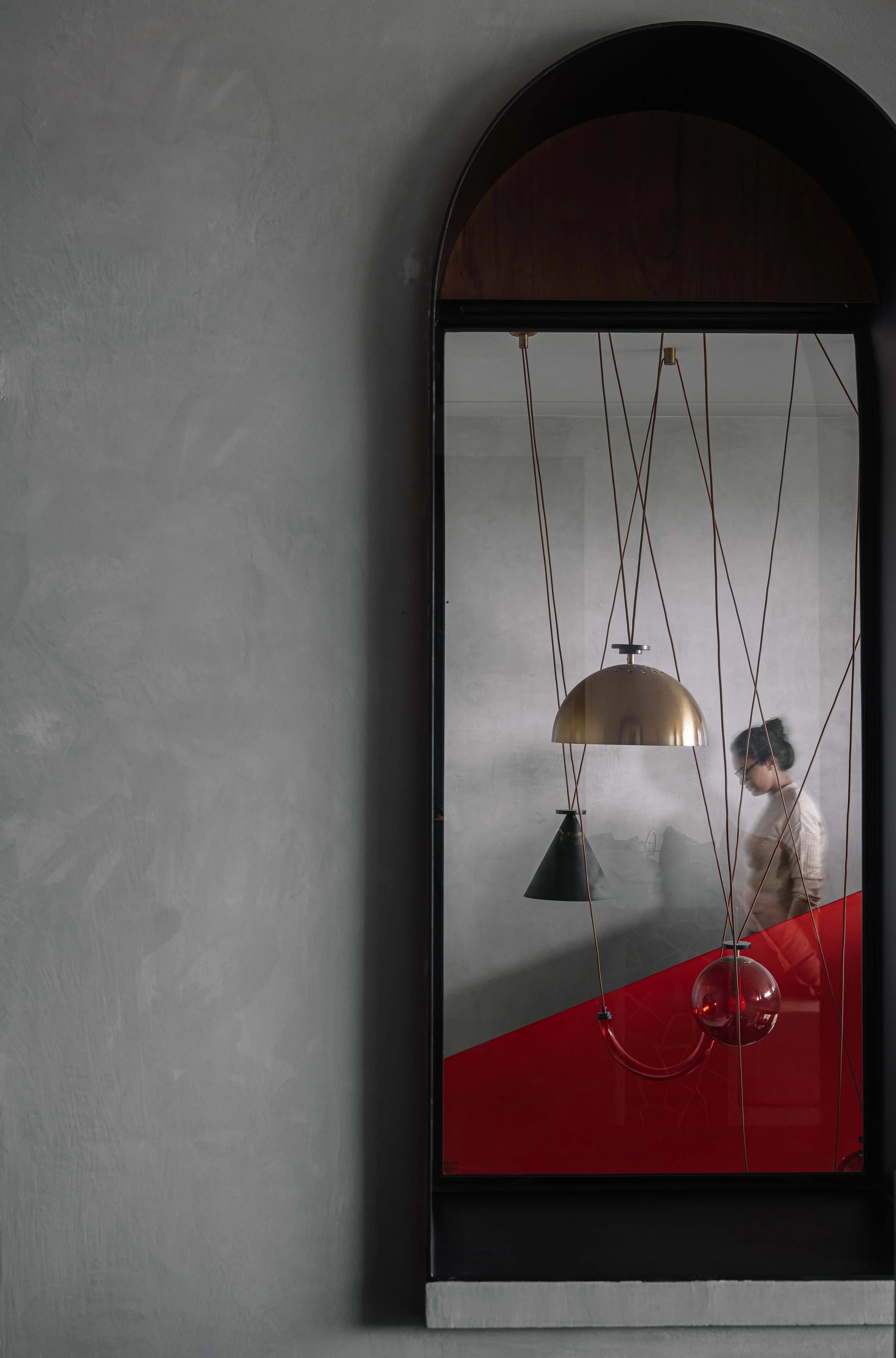 Arched interior window with sculptural pendant lights and bold red accents at Gardens in the Sky, a Calicut residence designed by Workers of Art.