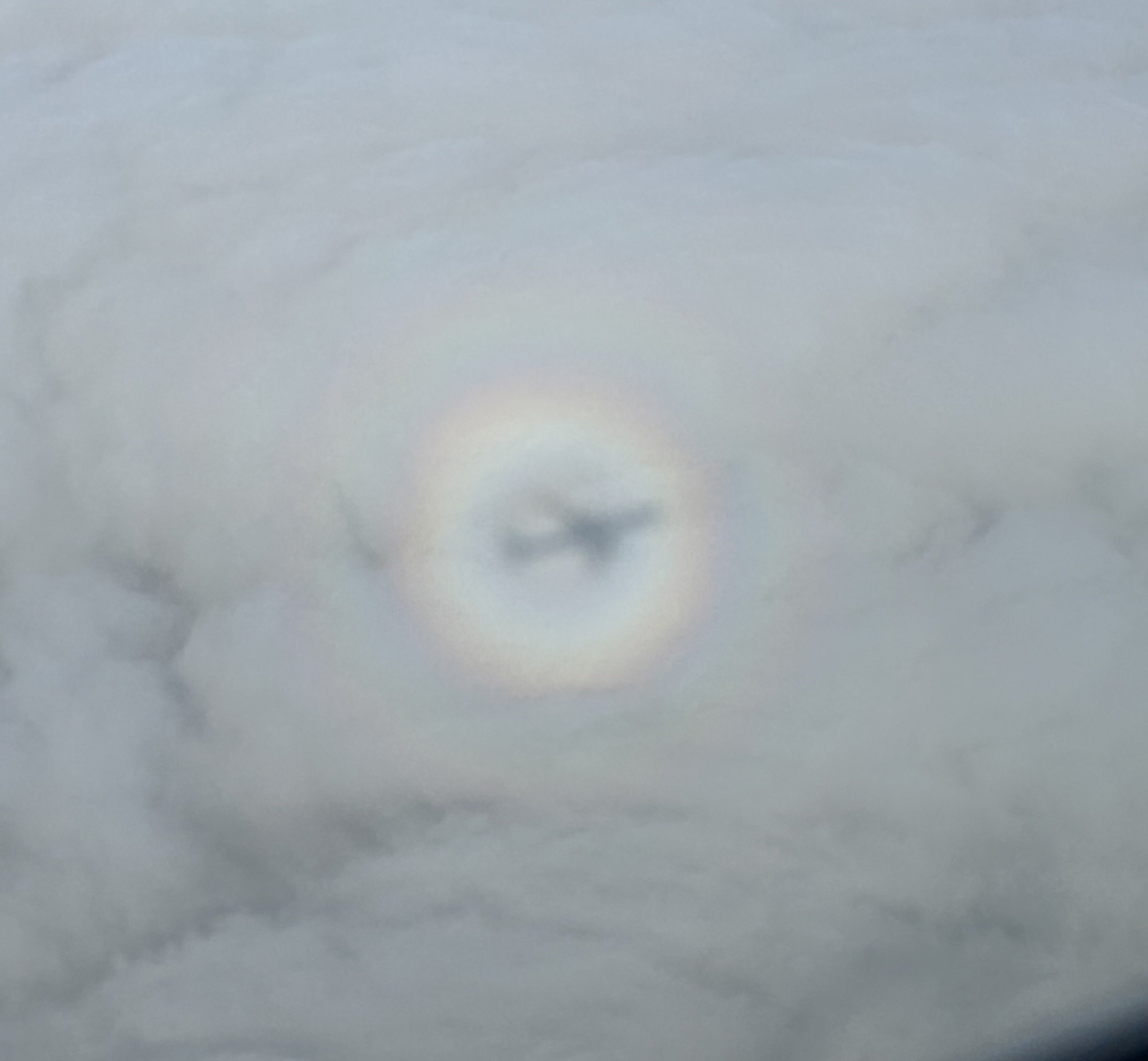 飛行機雲に虹色の円形の光の輪ができている空模様
