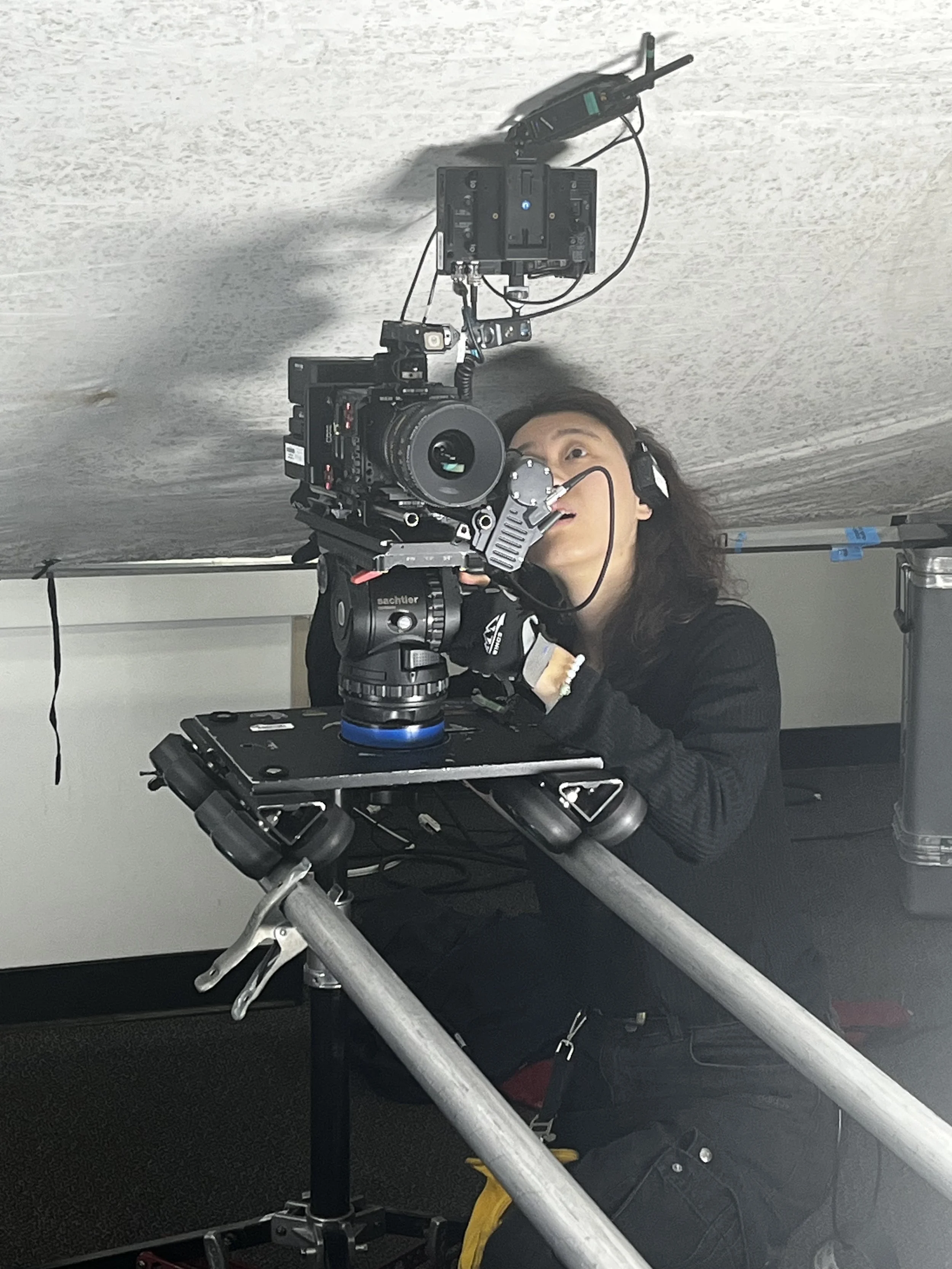 A person operating a professional camera rig under a table or low ceiling