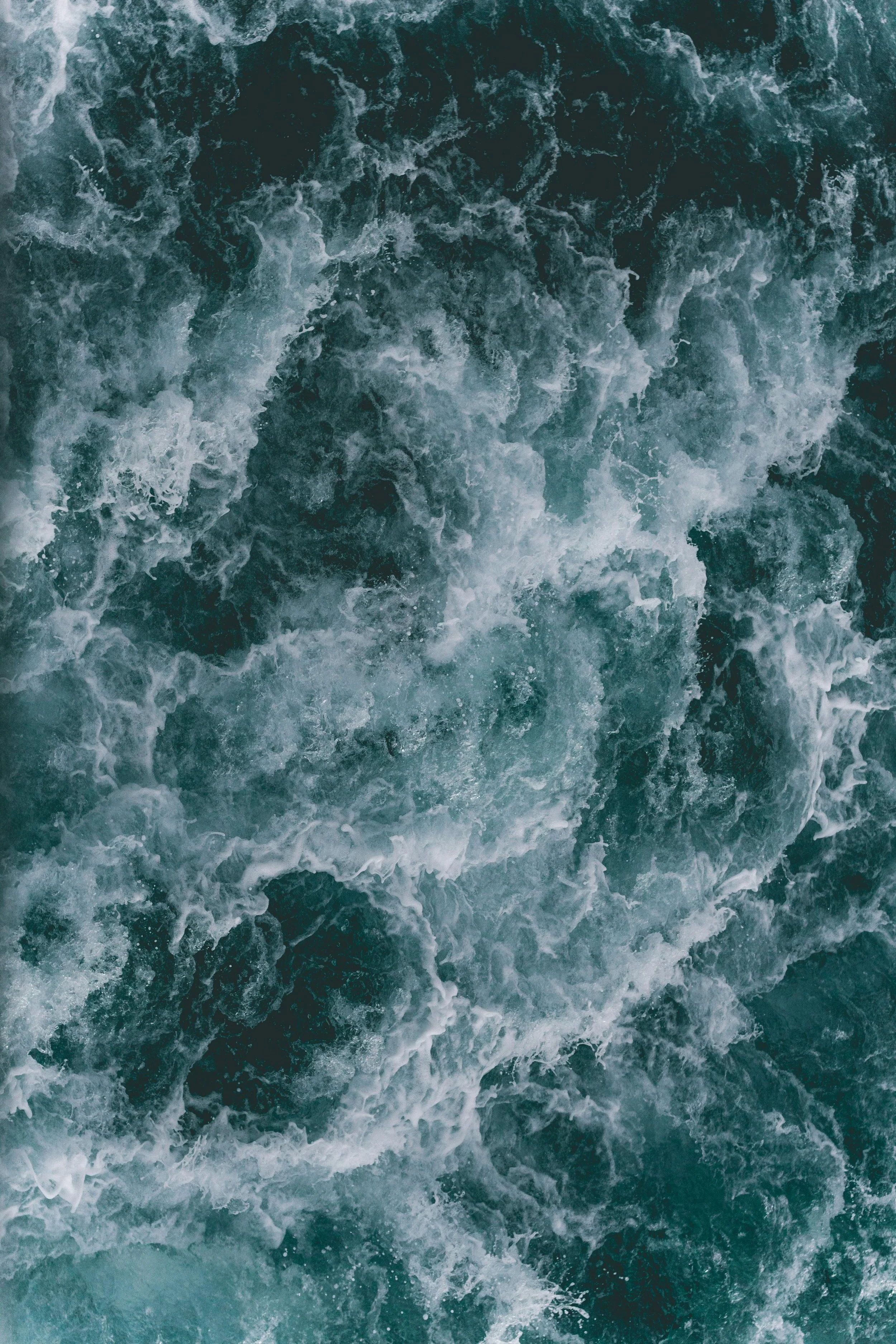 Aerial view of turbulent ocean waves with white foam.
