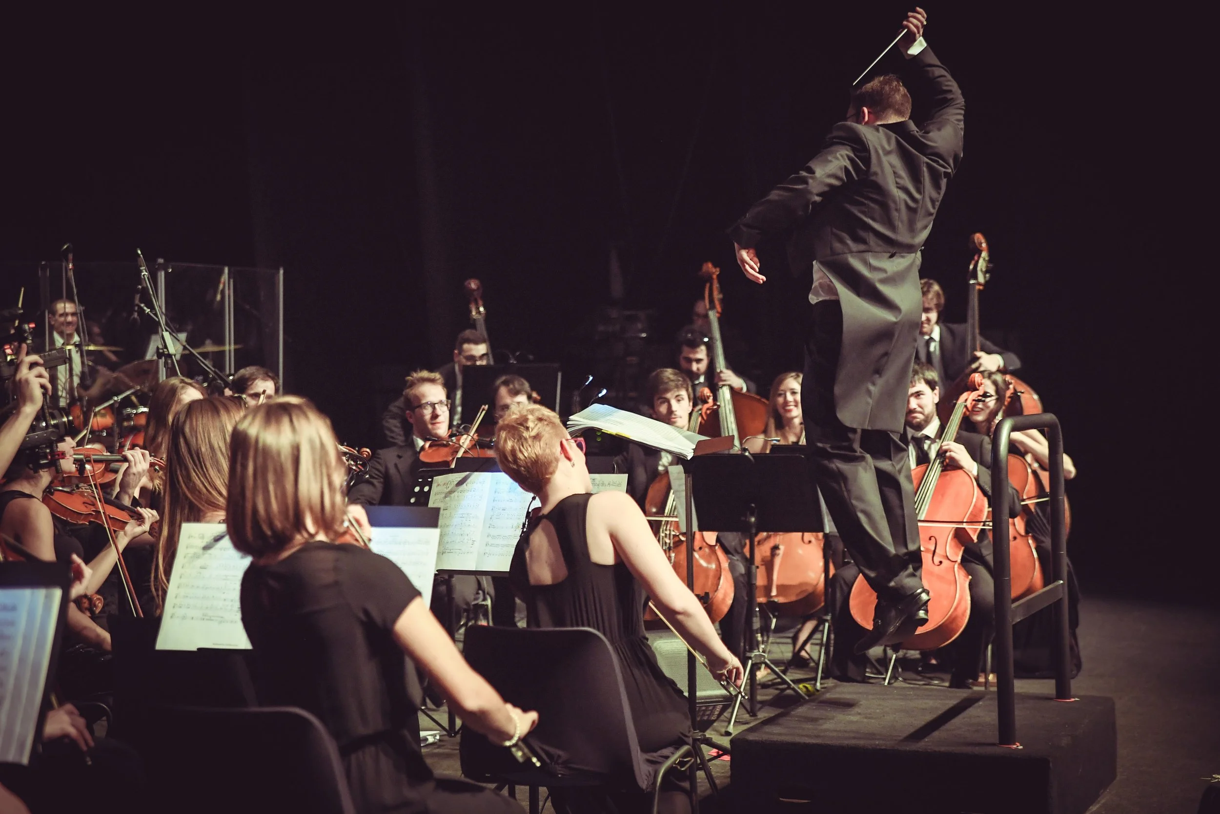 Il Direttore Simone Tonin salta mentre dirige energicamente l'orchestra
