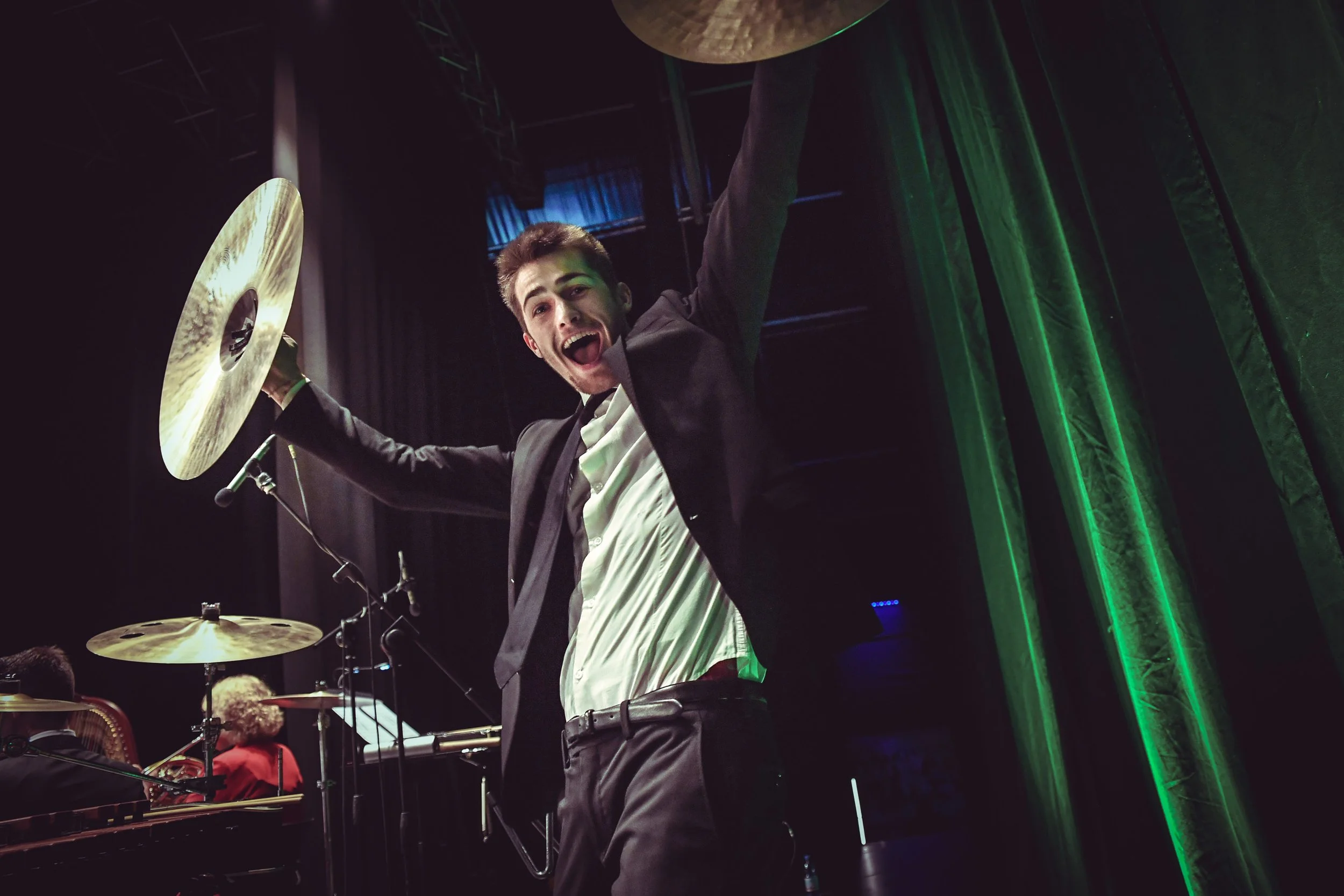 Un percussionista della Gaga Symphony Orchestra ora URANICA esulta sul palco alzando le braccia e tenendo i due piatti in mano
