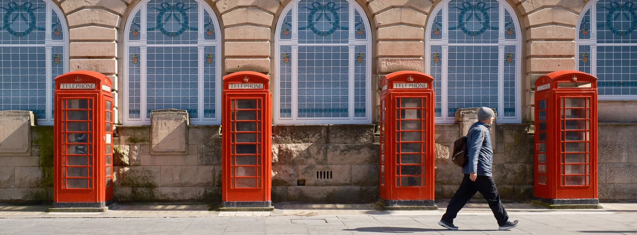 Man walking past a row of UK phone boxes in Blackpool