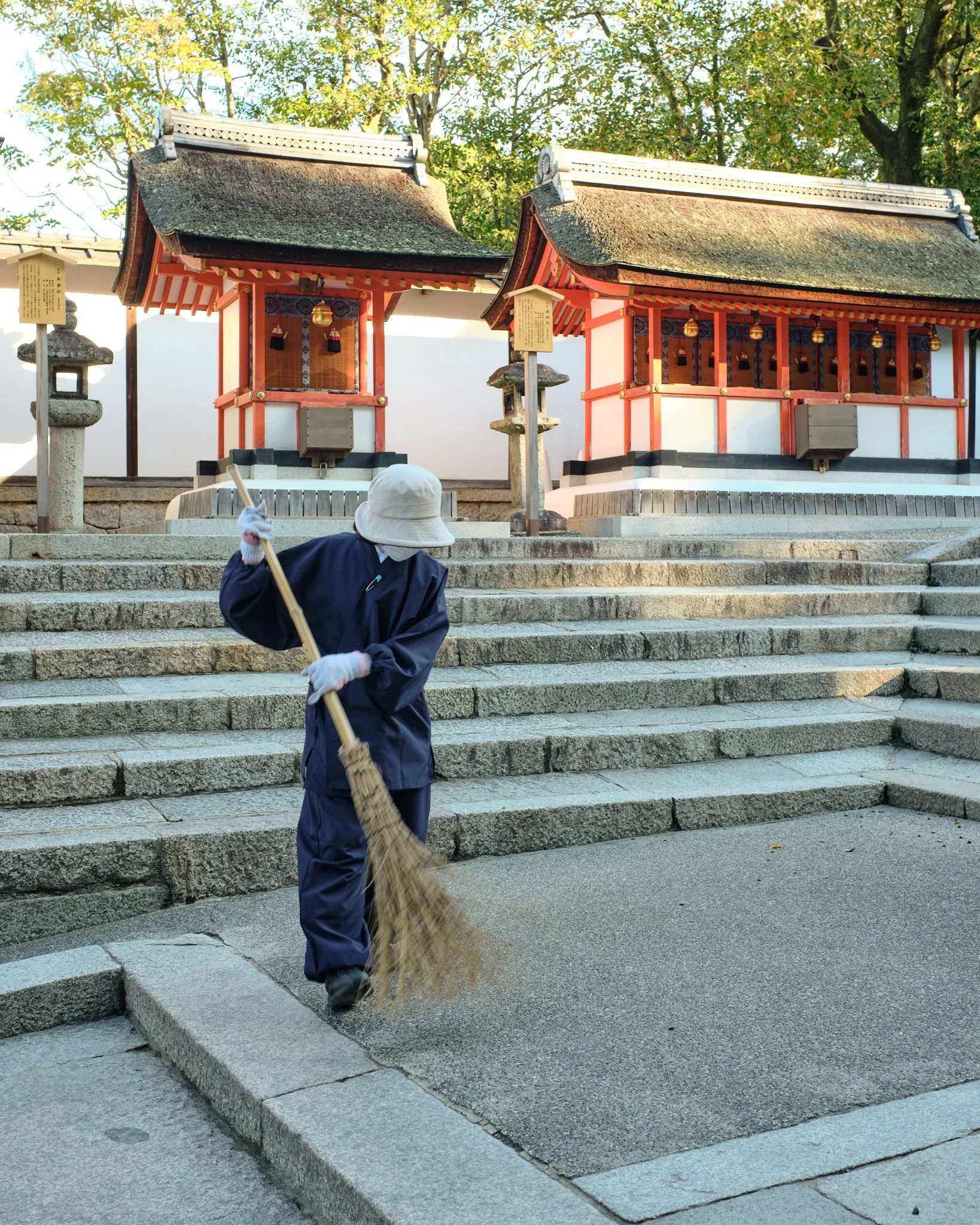 Worker sweeps the pathways surrounding Fushimi Inari Shrine in the early morning before the crowds of tourists arrive